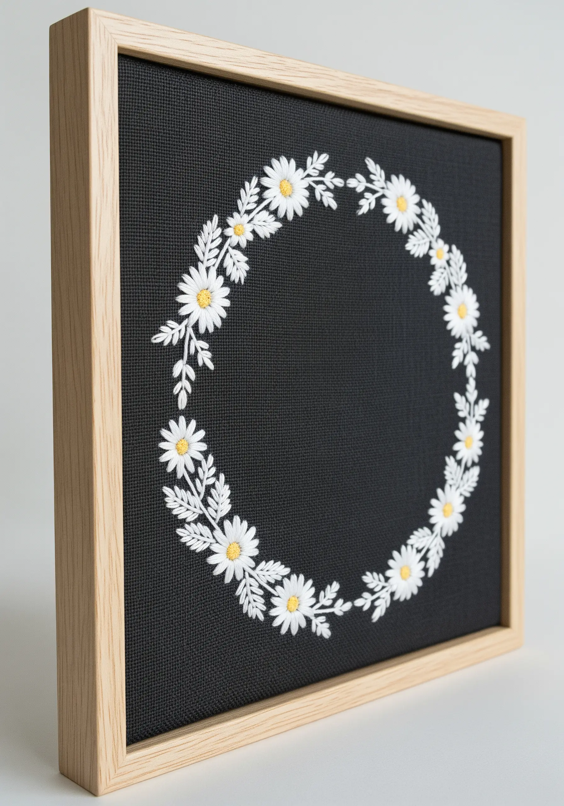 A delicate wreath of white daisies embroidered on black fabric and framed.