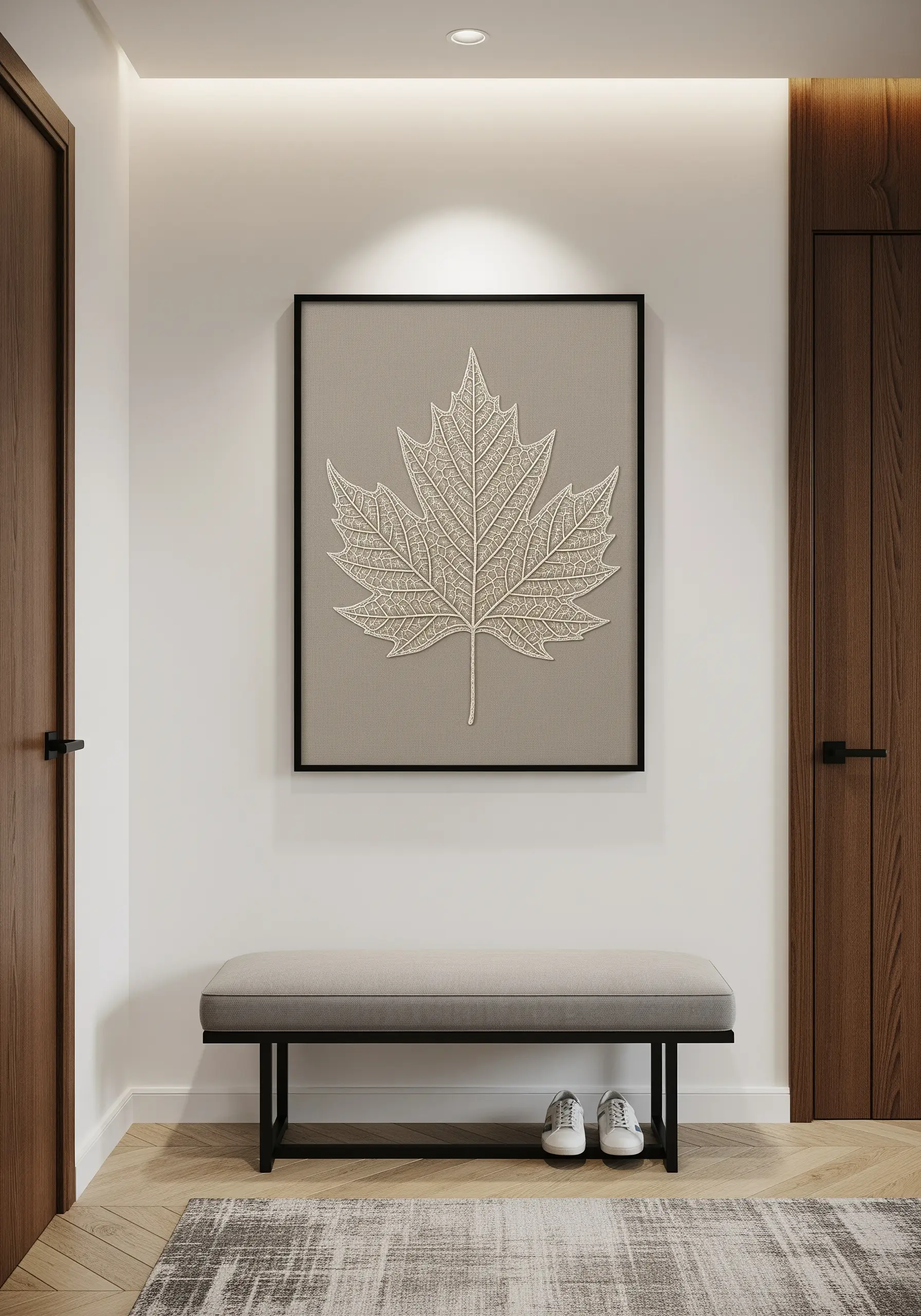 A large, framed embroidery of a maple leaf with intricate vein details in a single neutral color.