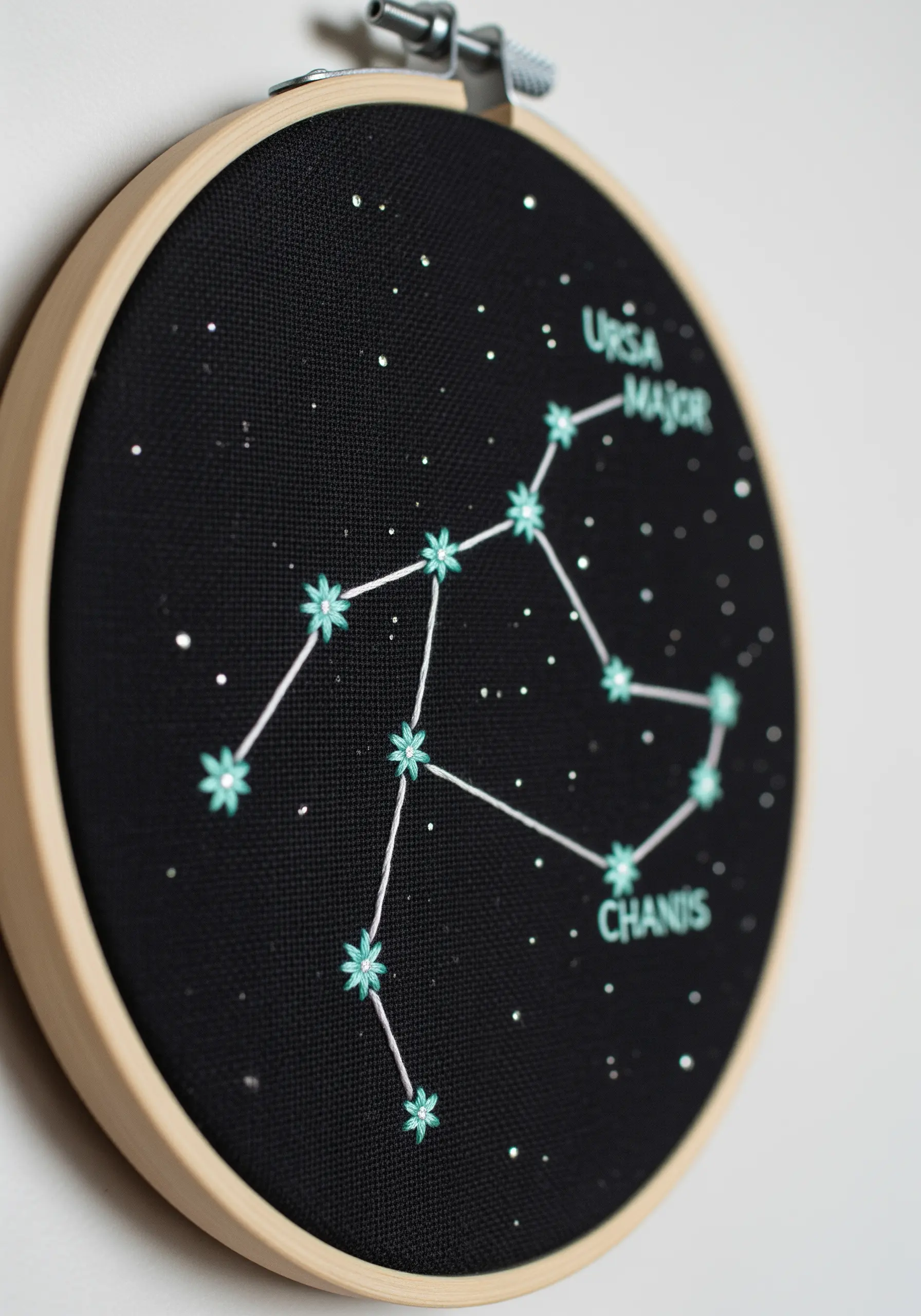 An embroidered constellation map on black fabric, with labels for Ursa Major.