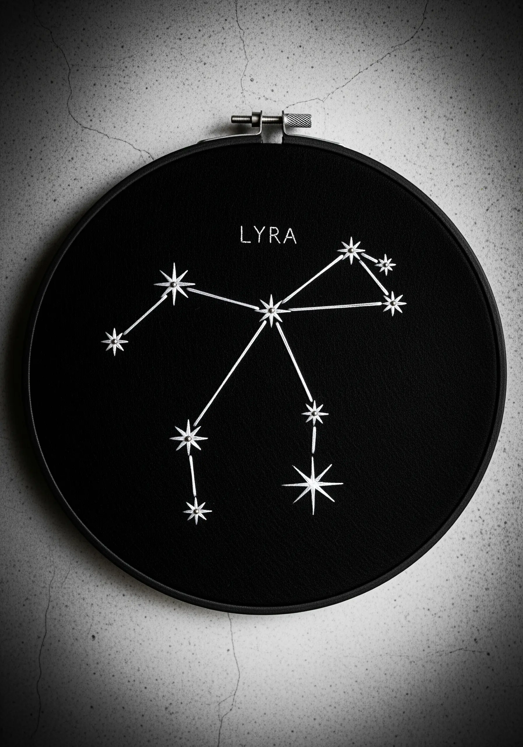 Lyra constellation embroidered with white thread on black fabric in a black hoop.