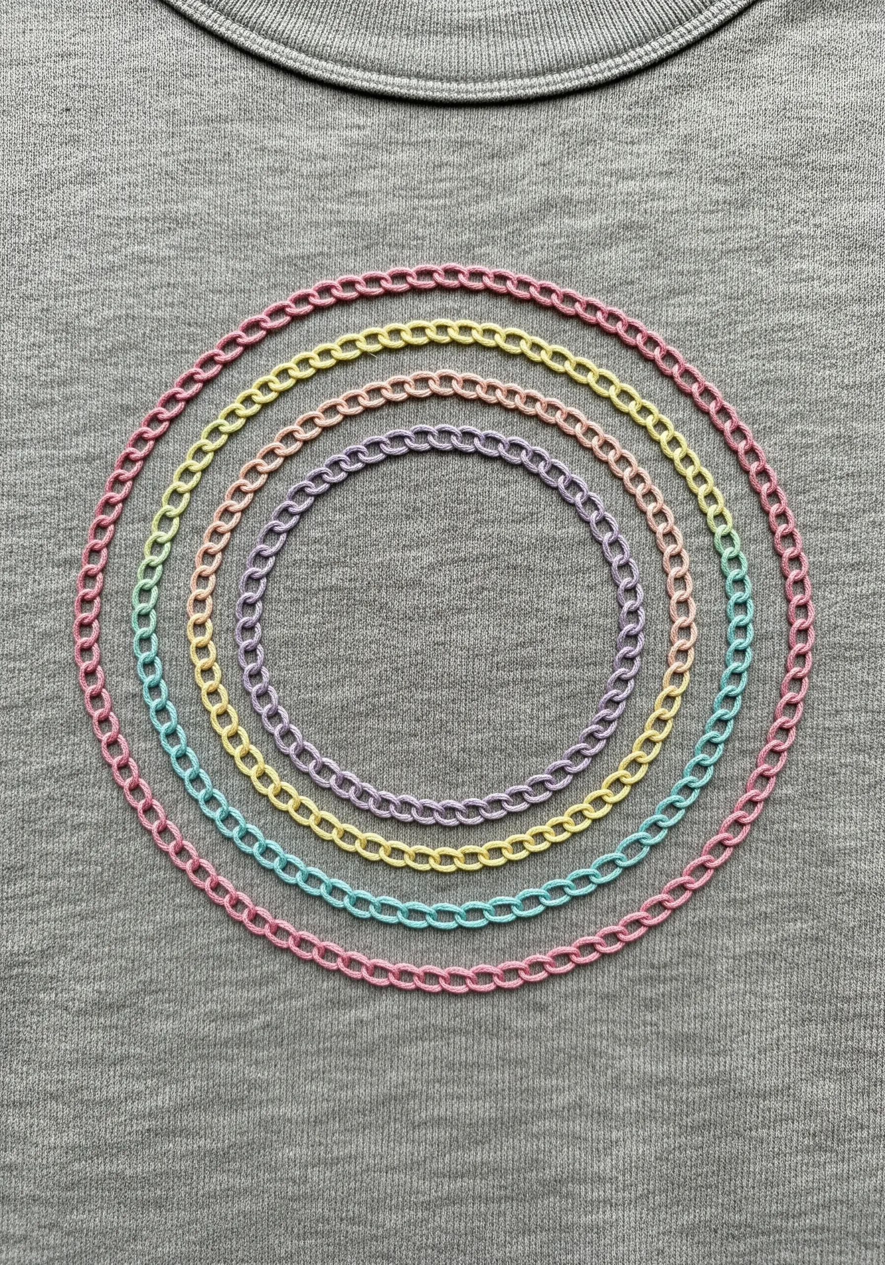 Concentric circles in pastel-colored chain stitch on a grey knit sweatshirt.