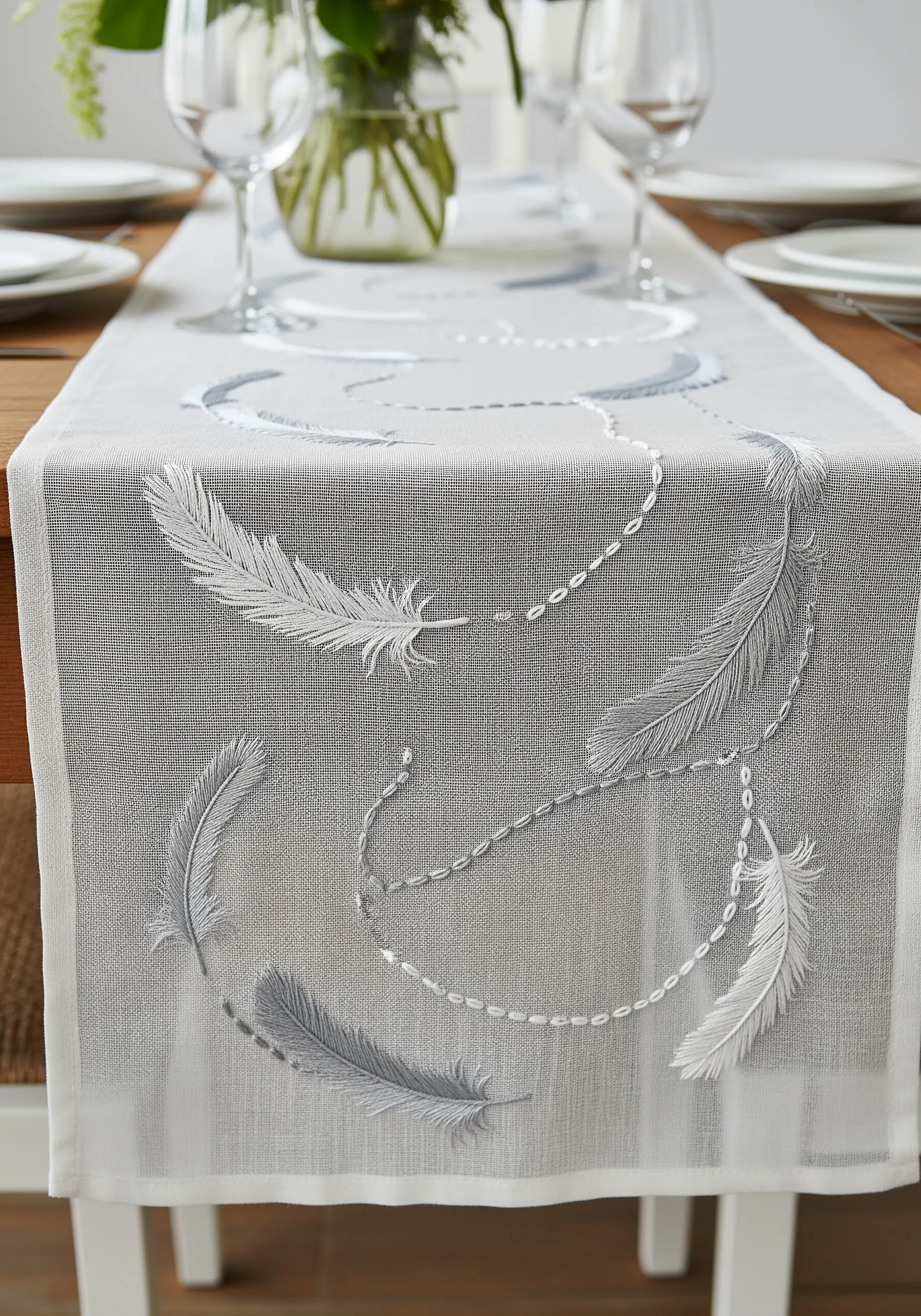 Delicate white and gray feathers embroidered on a sheer, lightweight table runner.