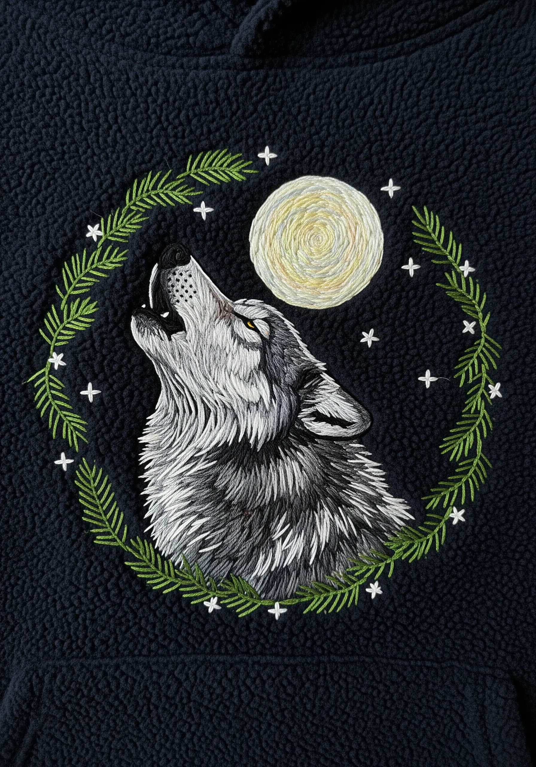 A realistic wolf howling at the moon embroidered on a dark fleece hoodie.
