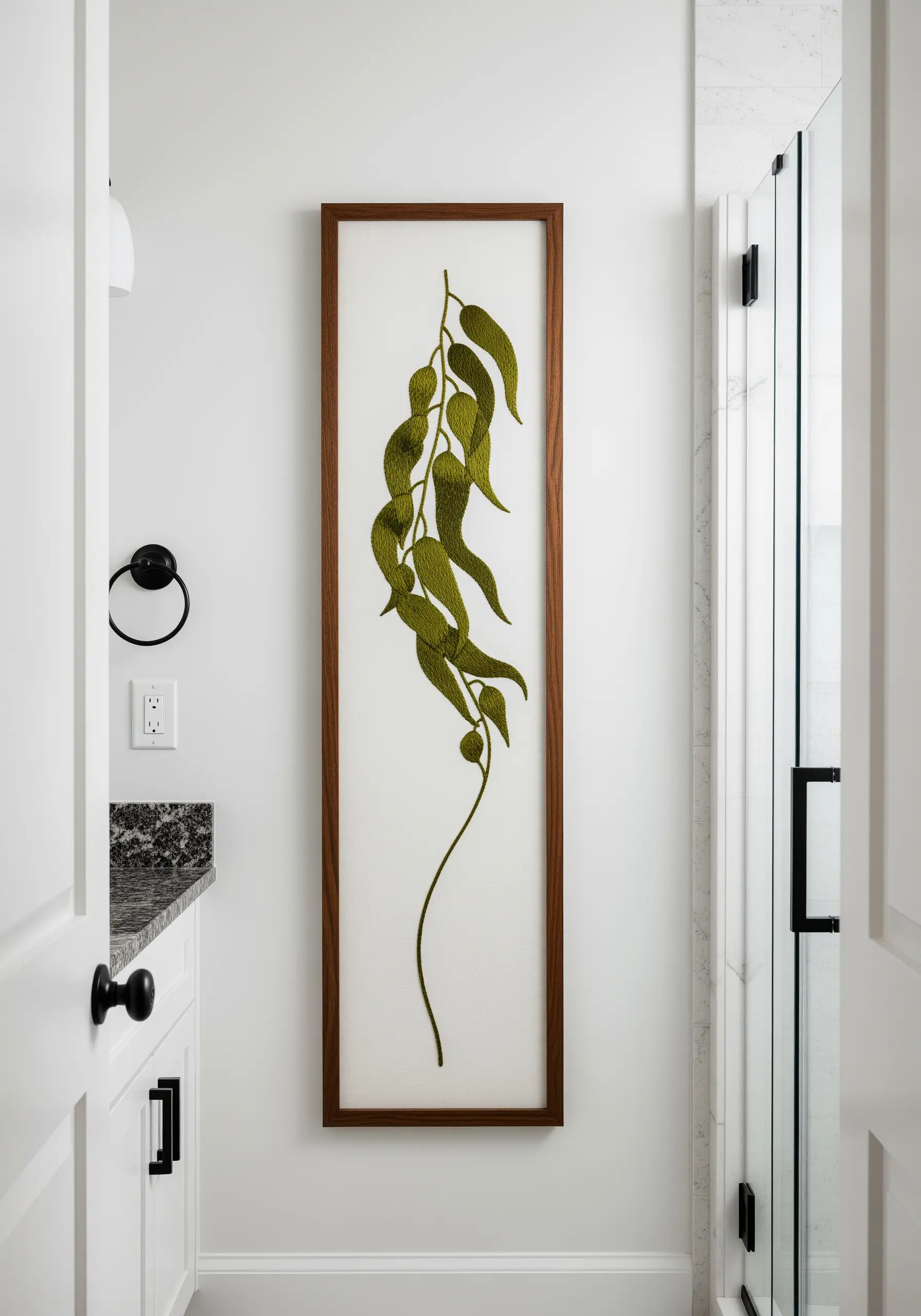 A long, vertical embroidery of a green kelp strand with flowing leaves in satin stitch.