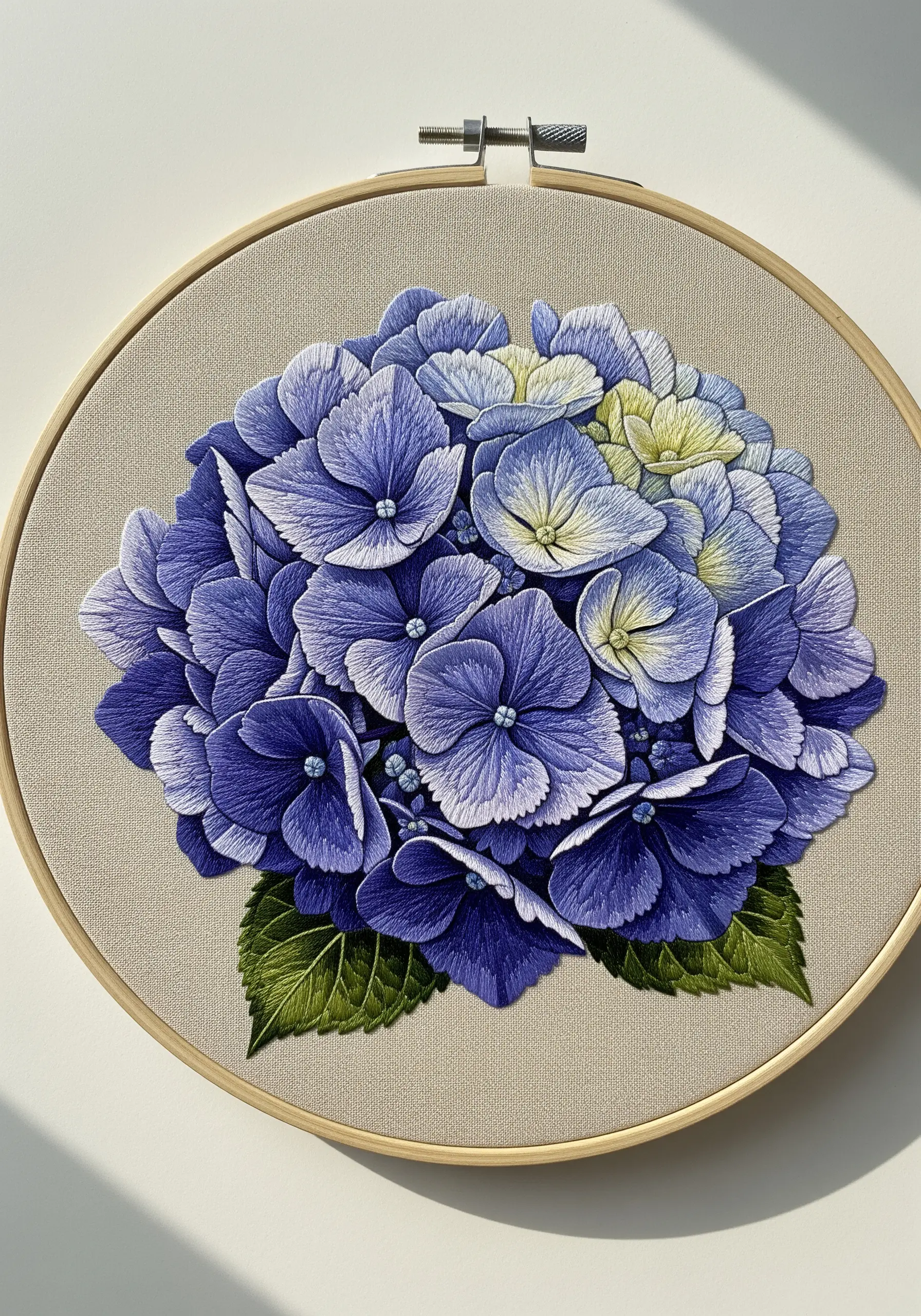 Detailed thread-painted blue hydrangea with deep shadows and light highlights in a wooden hoop.
