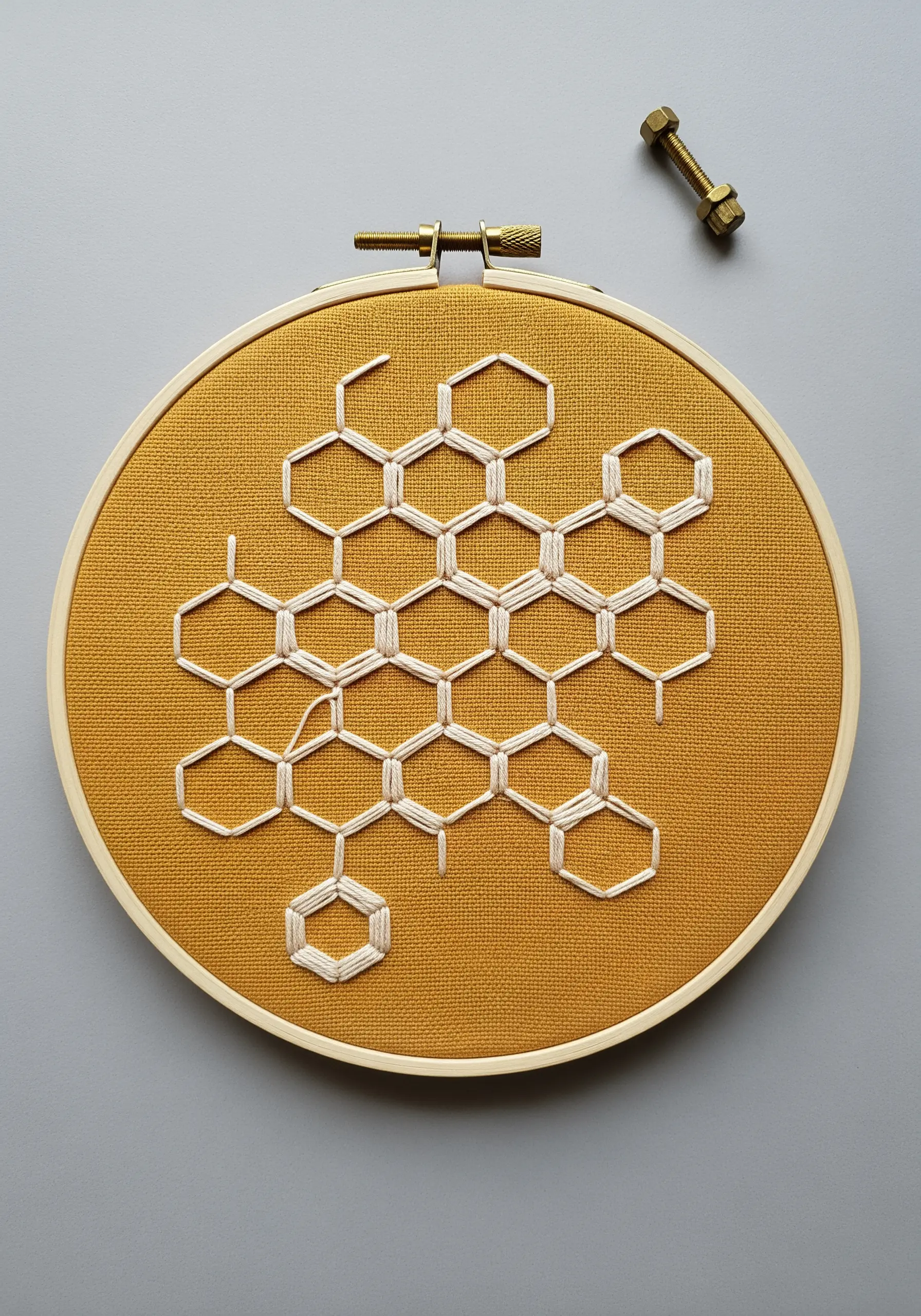 White backstitched honeycomb pattern on a mustard yellow background.