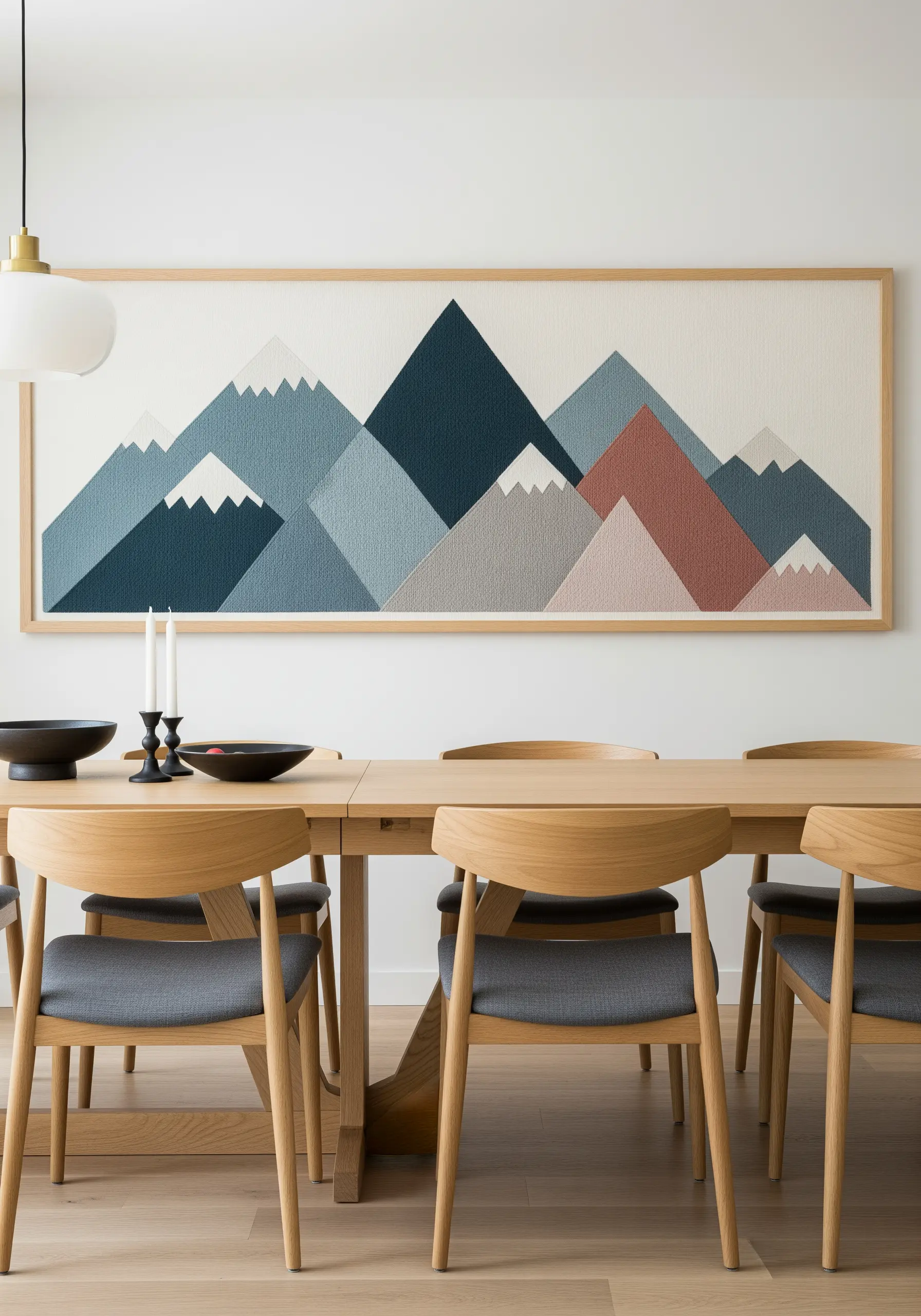A large framed embroidery of geometric mountains in shades of blue, grey, and rose.