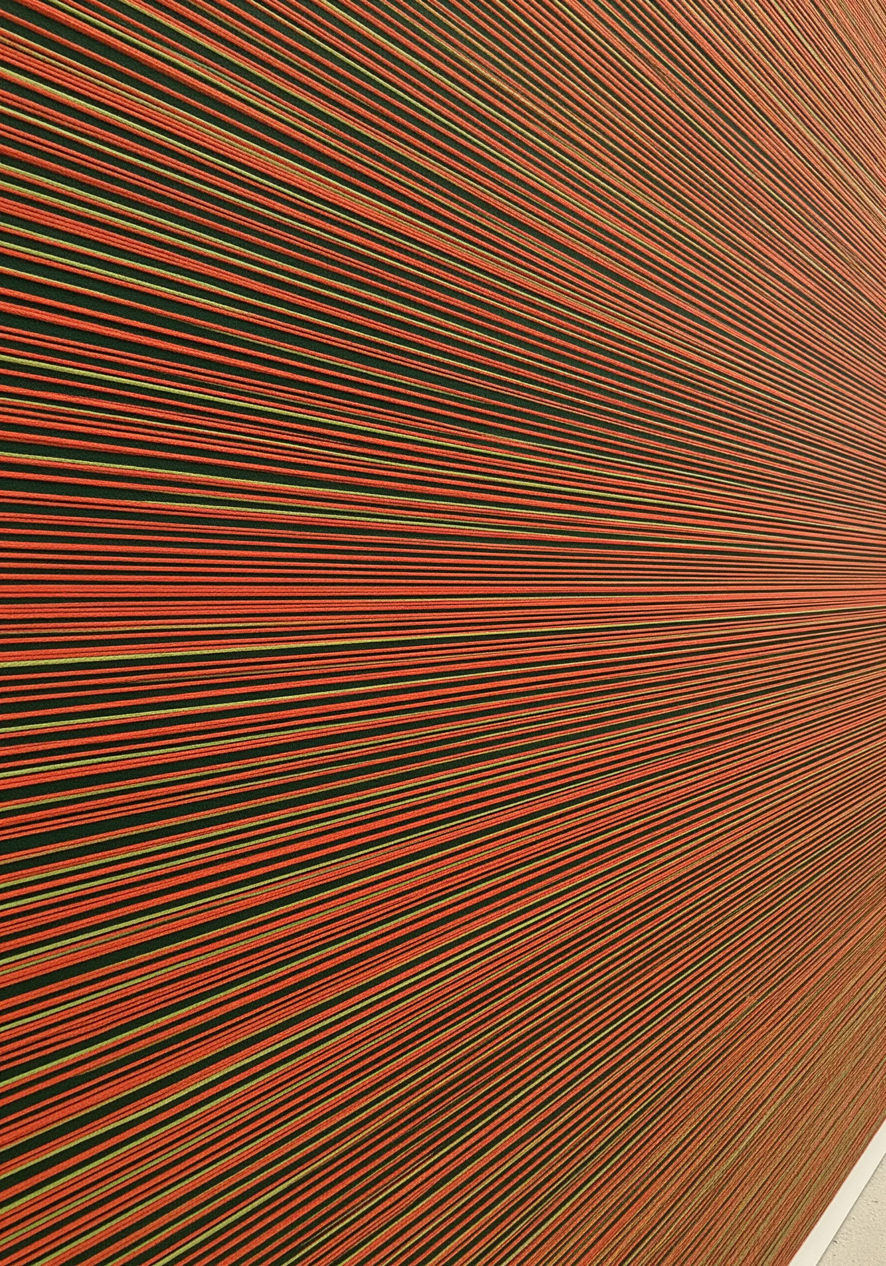 A close-up of tightly stretched horizontal threads in orange, yellow, and black, creating a vibrant texture.