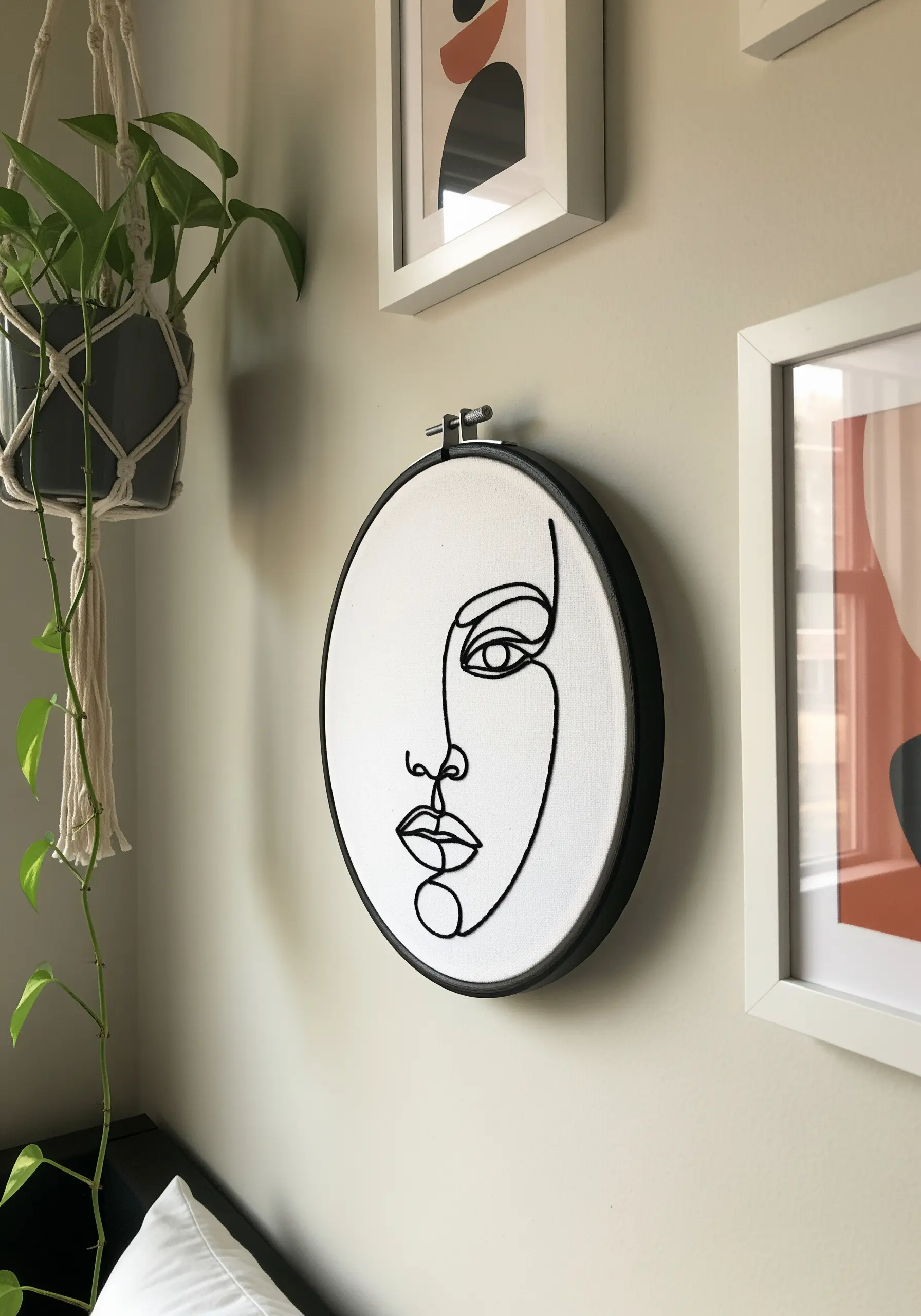 Minimalist single-line face profile embroidered in bold black thread on white canvas.
