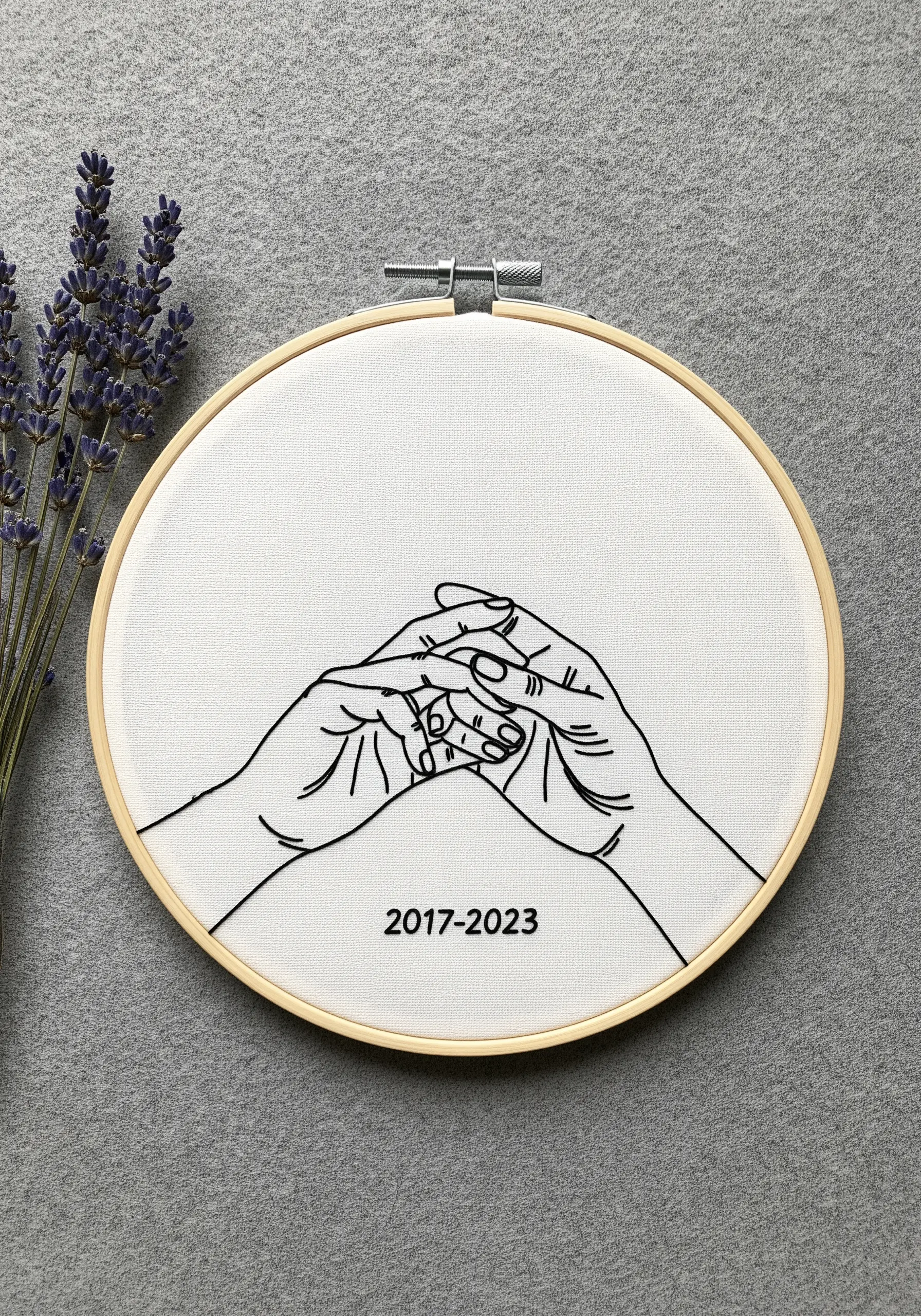 Clean black thread embroidery of two hands holding, with anniversary dates stitched below.
