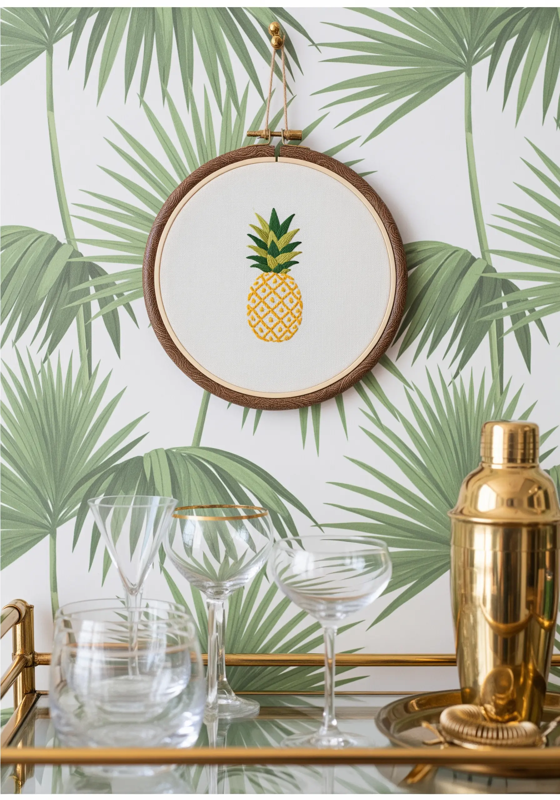 A cross-stitched pineapple on white fabric, displayed in a dark wood hoop.