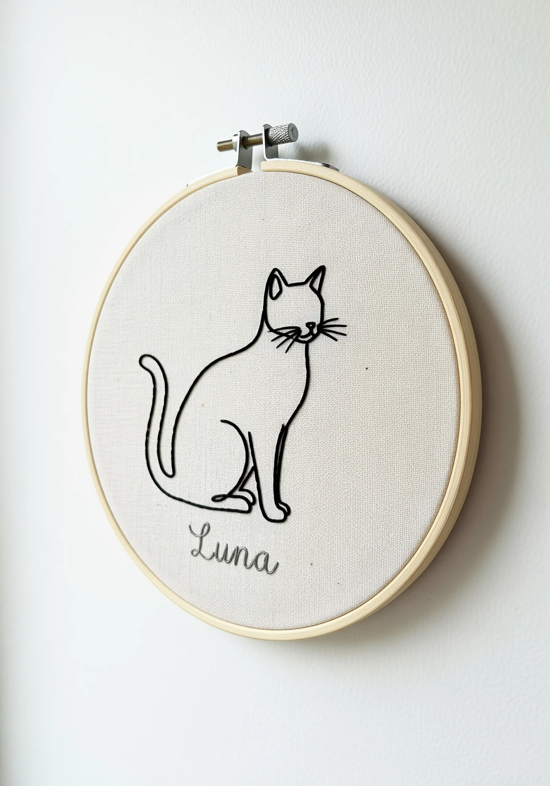 Minimalist black line art embroidery of a sitting cat named Luna in a hoop.