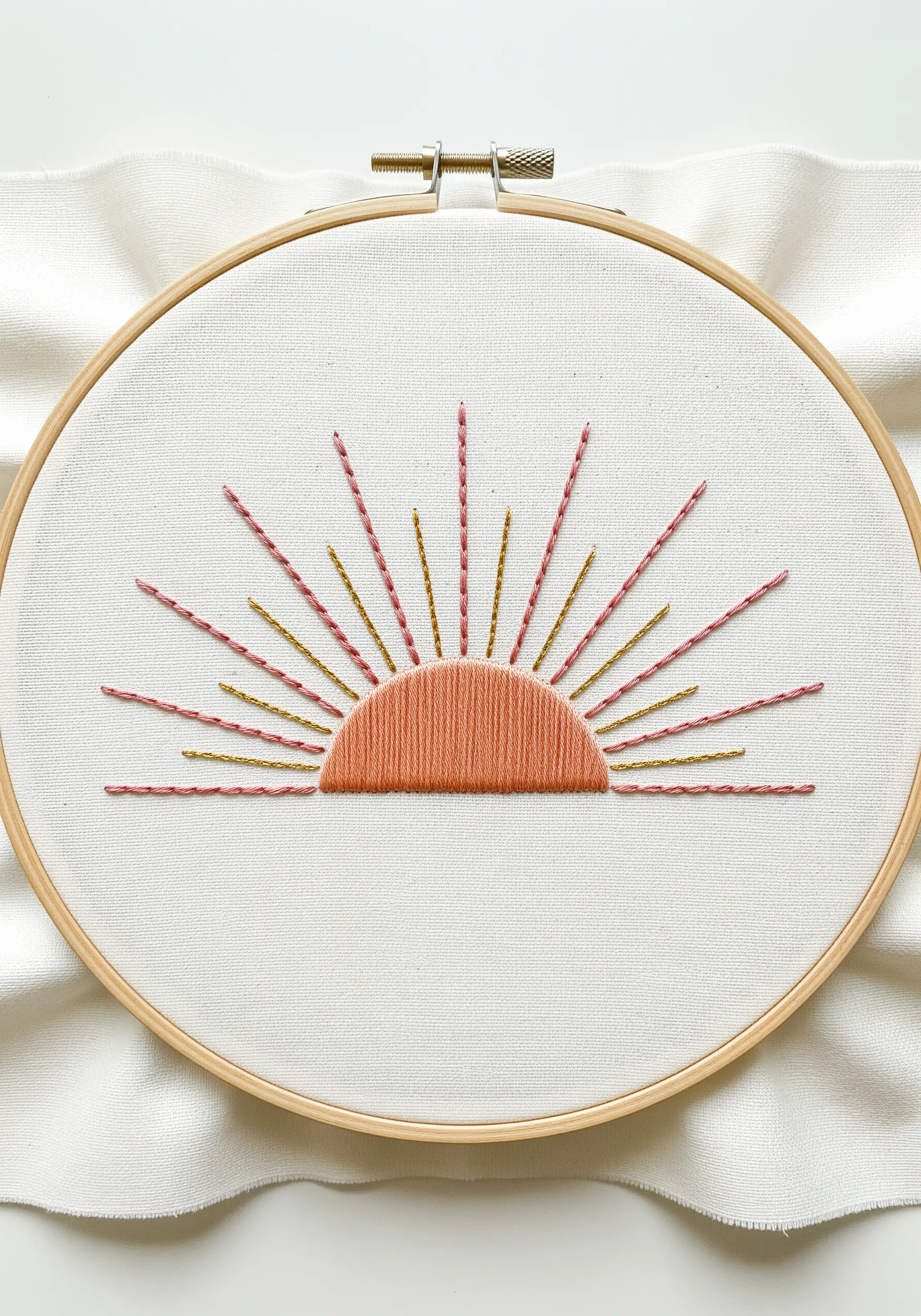 Abstract sunrise embroidery with a satin stitch sun and radiating lines.