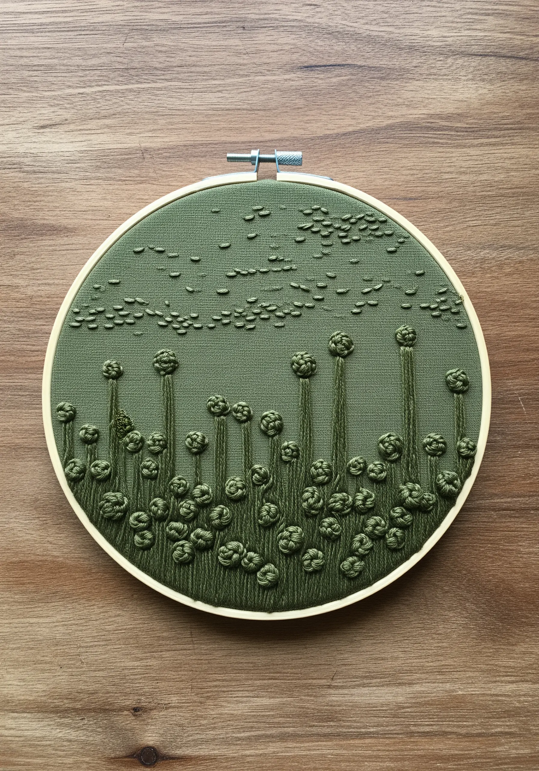 Monochrome green embroidery of abstract botanicals on matching green fabric, using bullion knots.