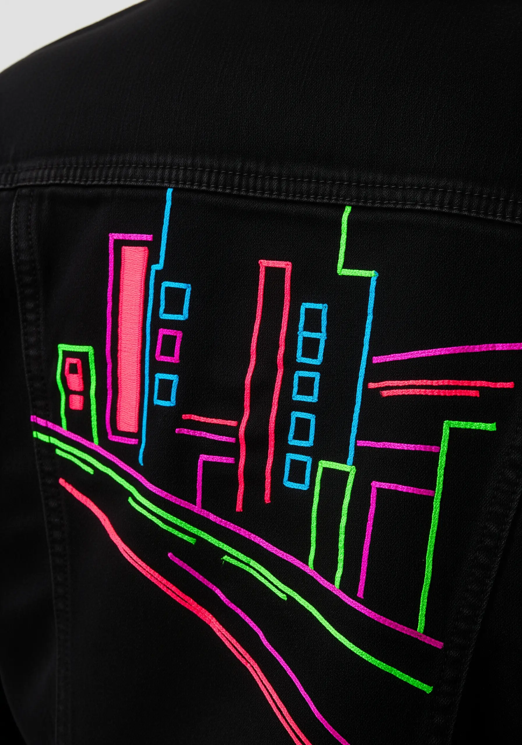 Neon line art embroidery of a cityscape on the back of a black denim jacket.