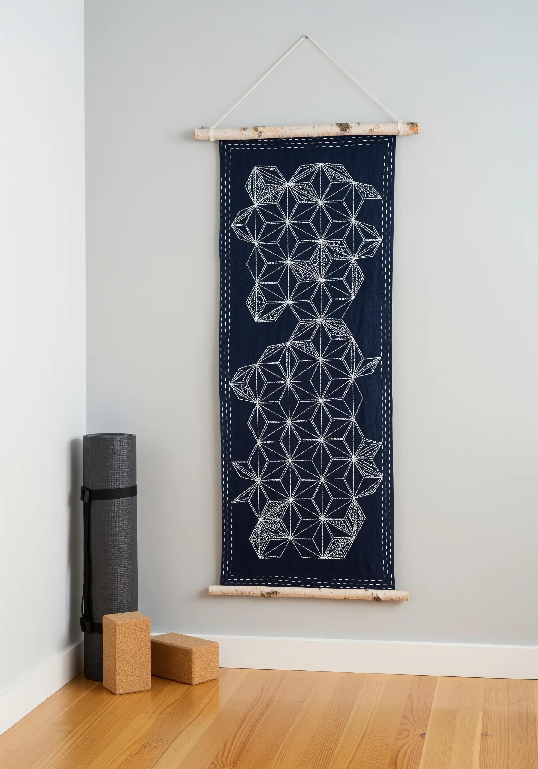 A Sashiko wall hanging with a white geometric Asanoha pattern stitched on dark blue fabric.