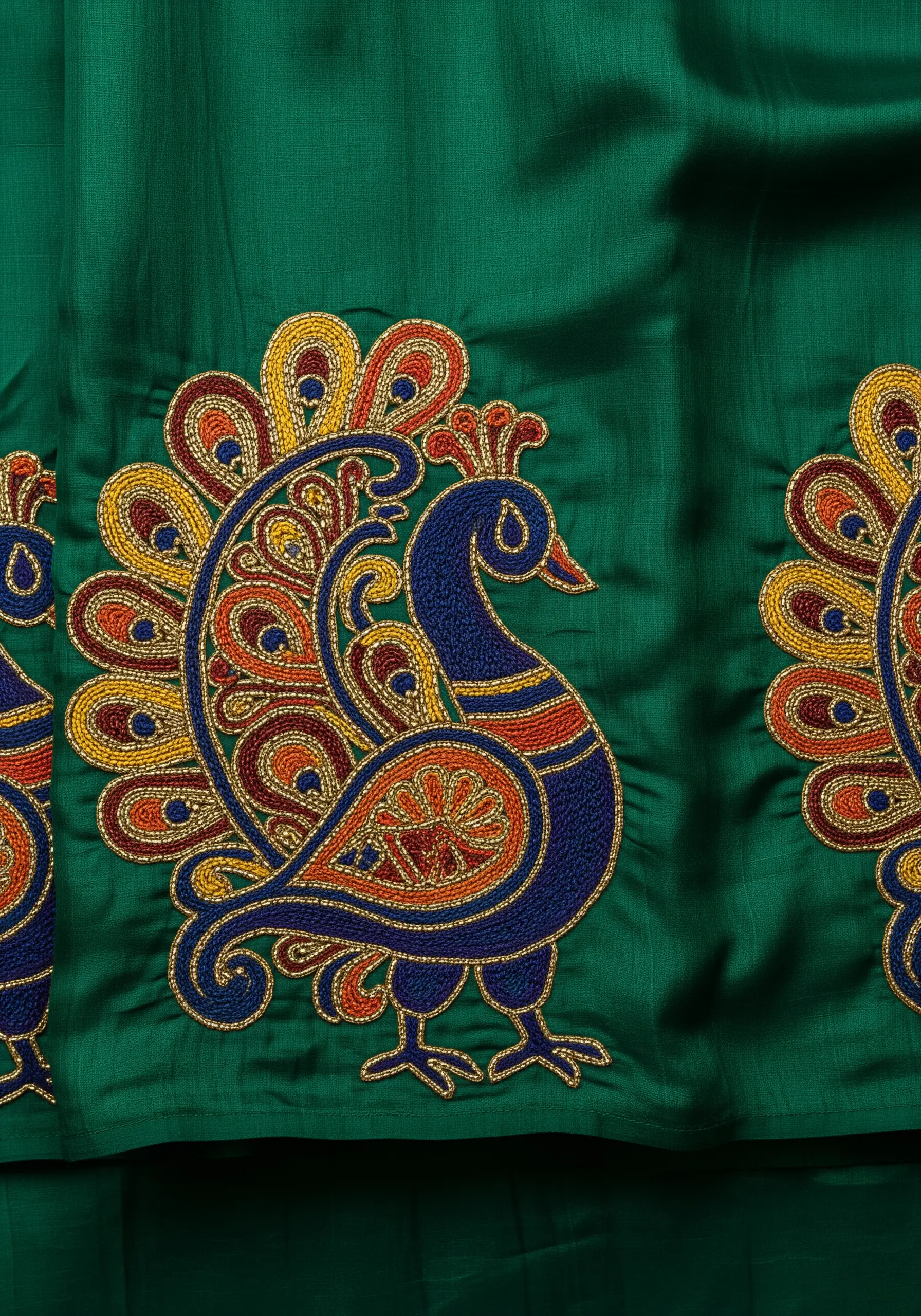 Stylized peacock motifs on a green fabric, with tails shaped like paisley patterns.