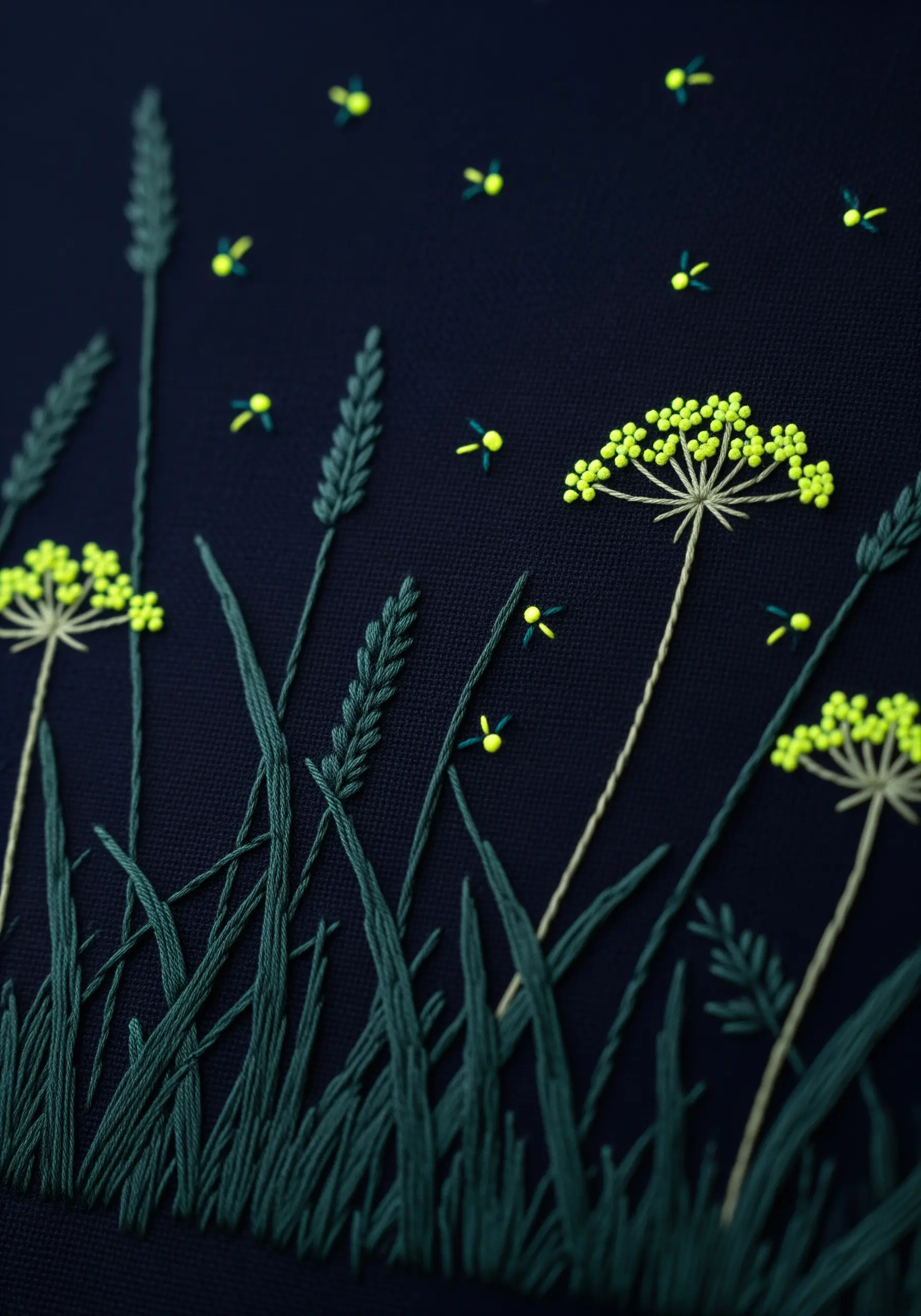 Close-up of embroidered fireflies using neon yellow thread on a dark navy background.