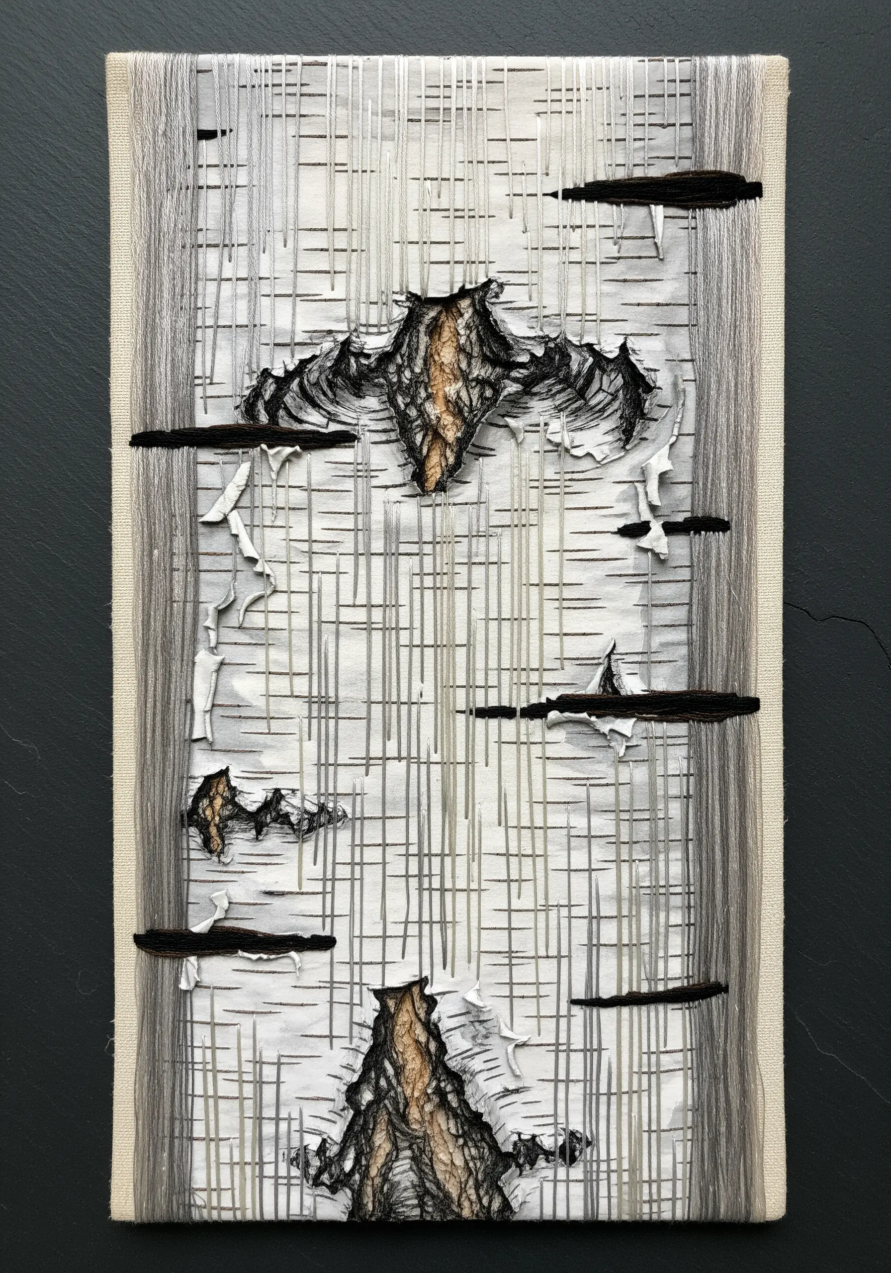 Abstract textile art representing birch bark with laid threads and peeling fabric pieces.