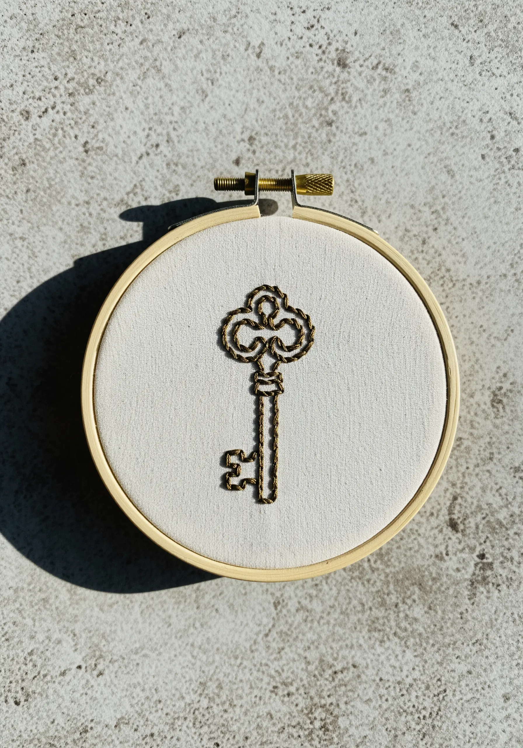 An antique-style key embroidered with chain stitch using metallic gold thread.