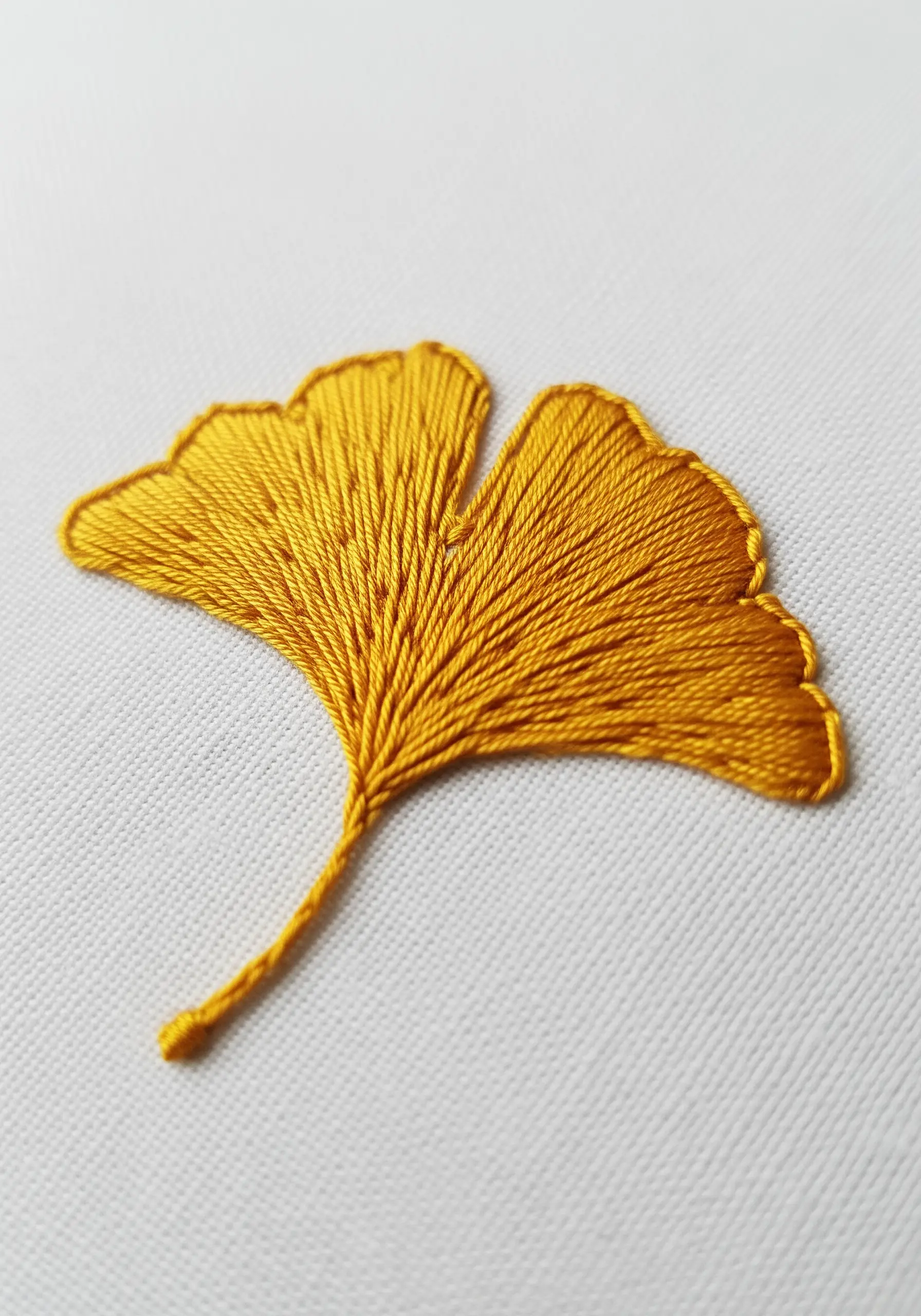 A golden yellow ginkgo leaf filled with directional long-and-short stitch.