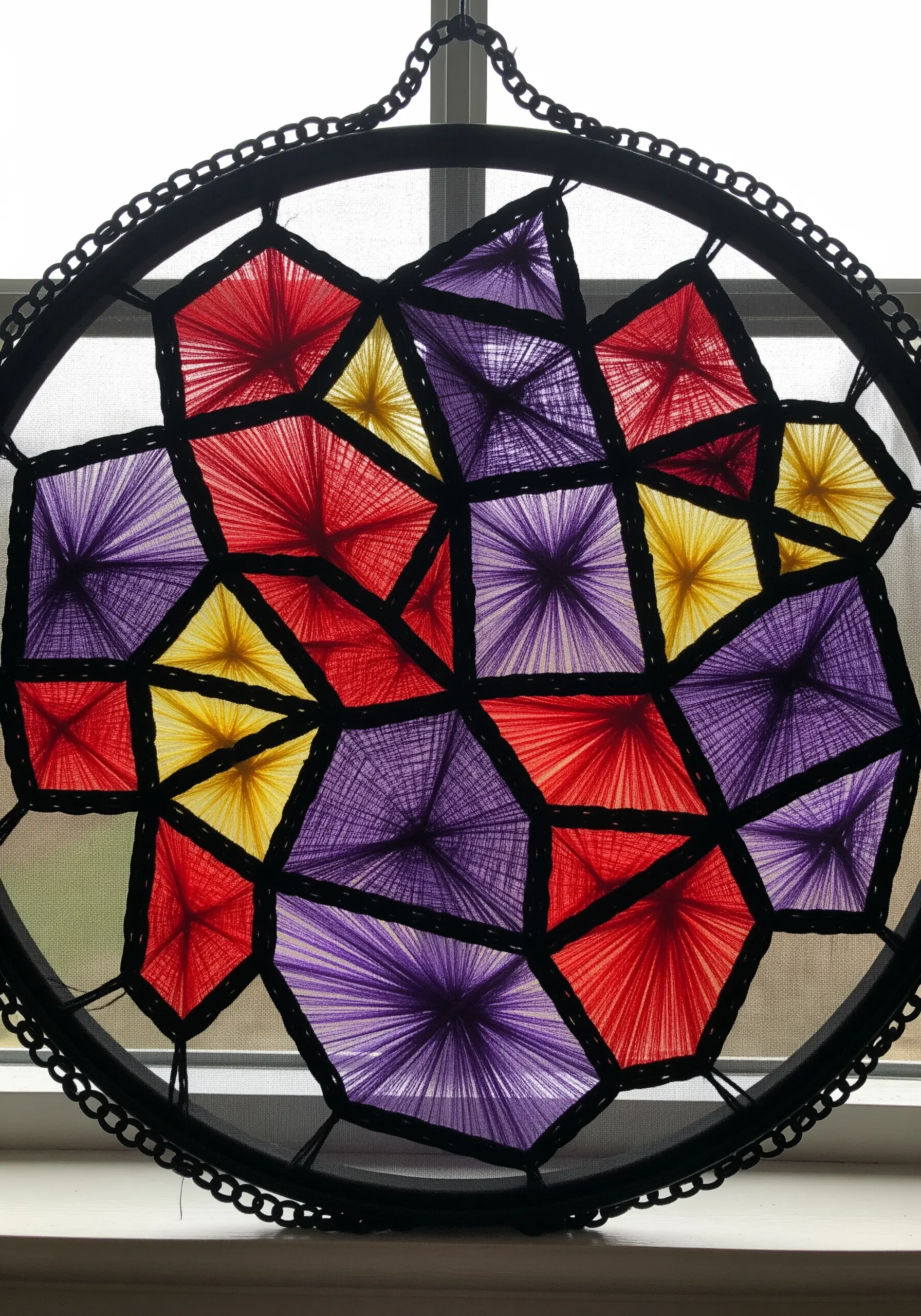 A string art design on sheer fabric resembling a stained-glass window with geometric panels.