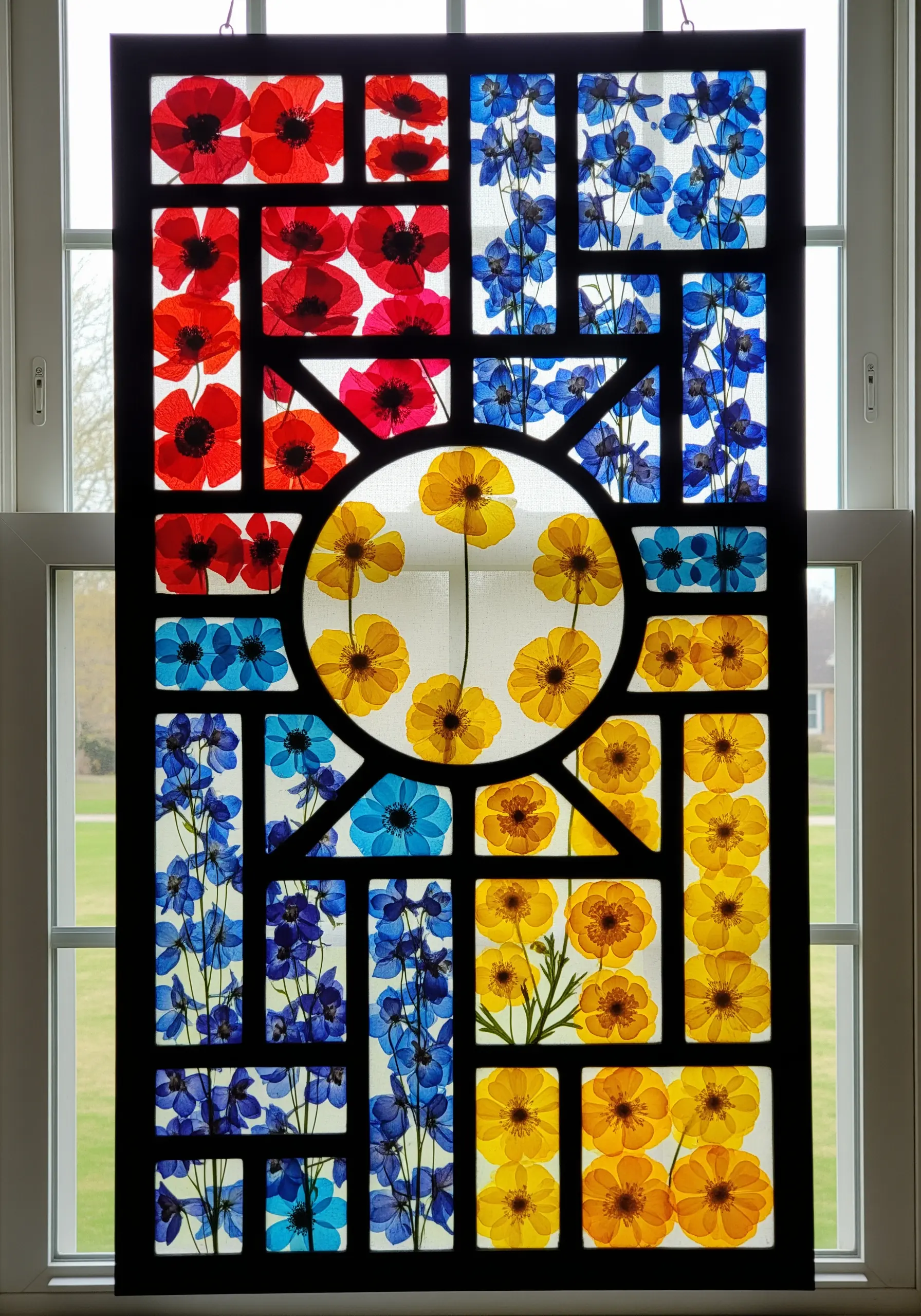 A panel with black embroidered lines creating a geometric pattern filled with colorful pressed flowers.