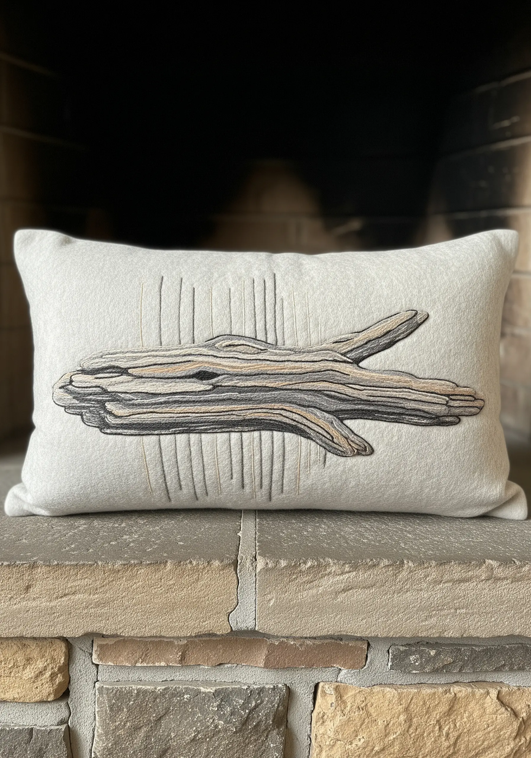 A realistic piece of driftwood embroidered with layered neutral threads on a felt pillow