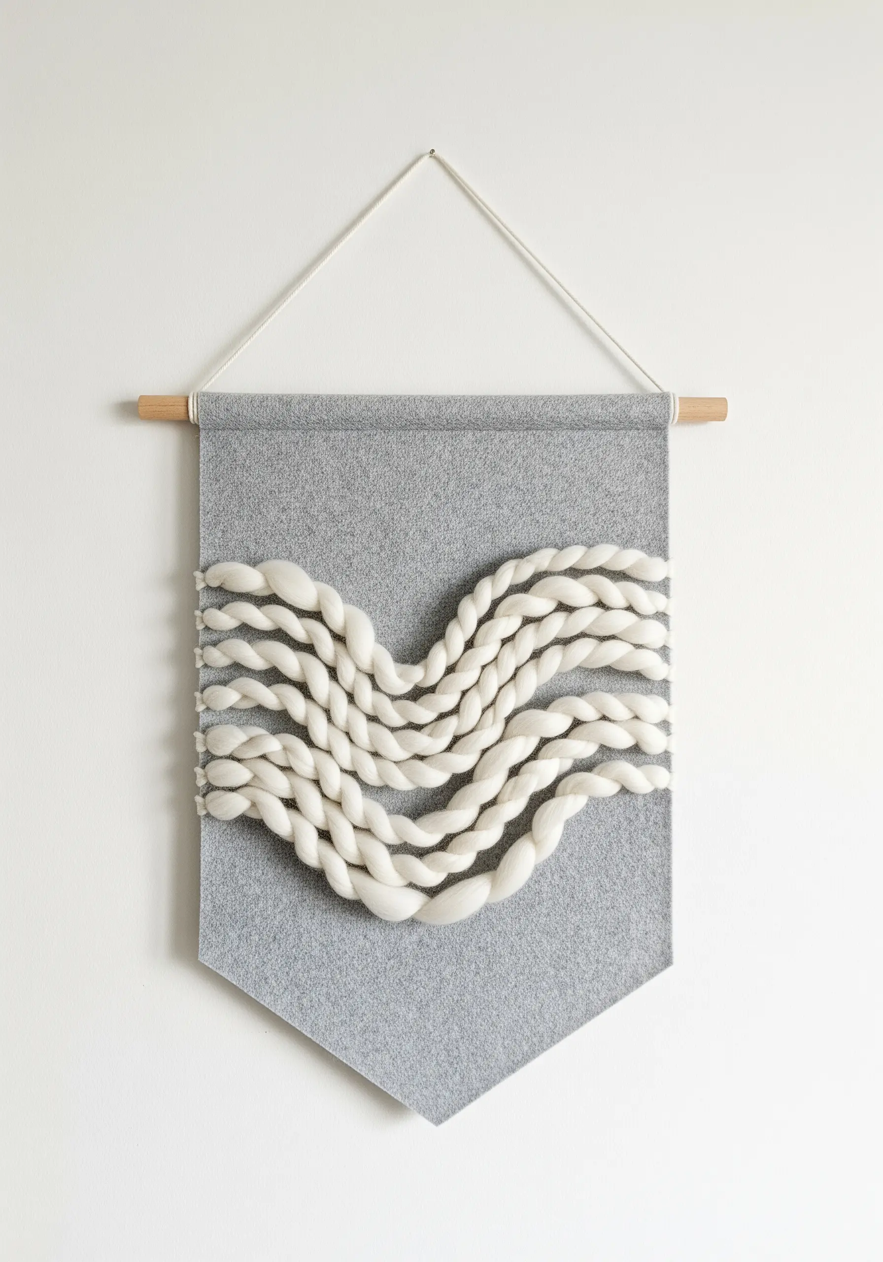 A grey felt banner with thick, twisted white wool roving attached in a wave pattern.