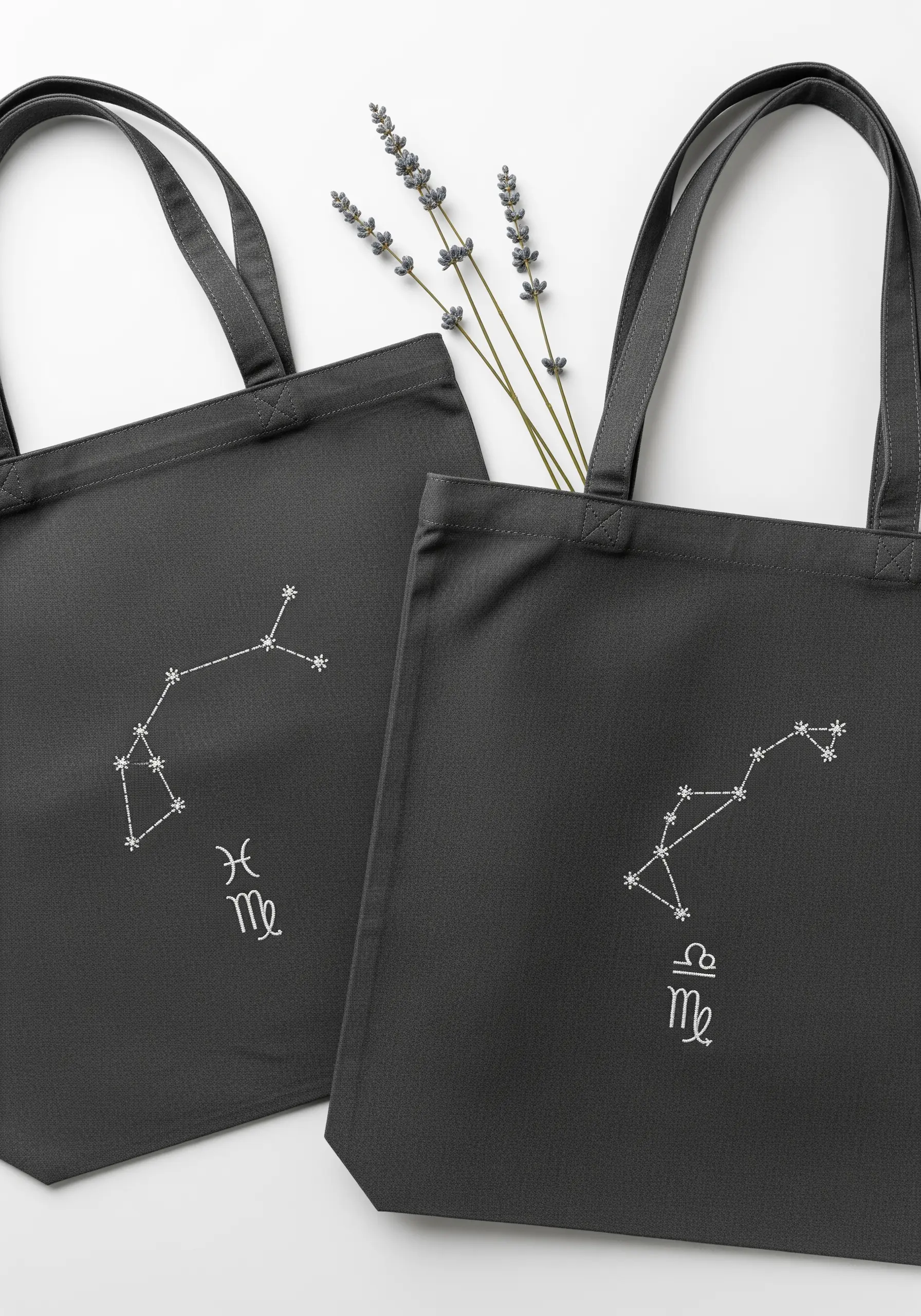Charcoal gray tote bags embroidered with minimalist zodiac constellations in white thread.