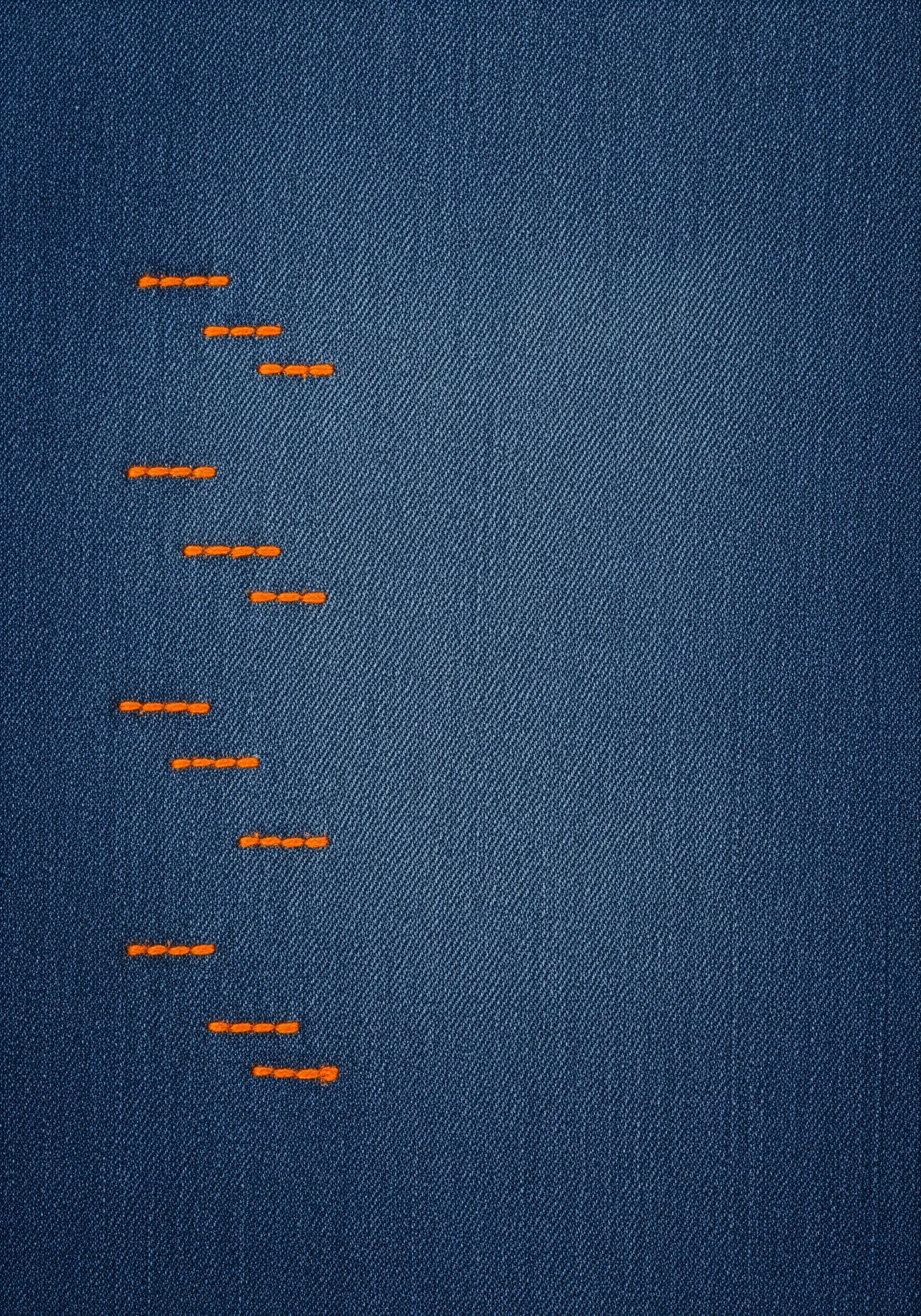 A curved line of short, horizontal orange running stitches on a dark denim background.
