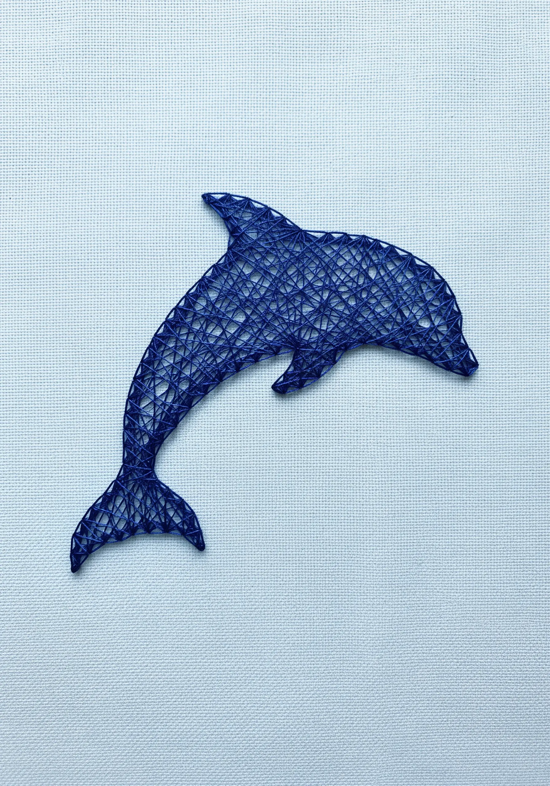 Minimalist string art dolphin silhouette in royal blue thread on light blue Aida cloth.