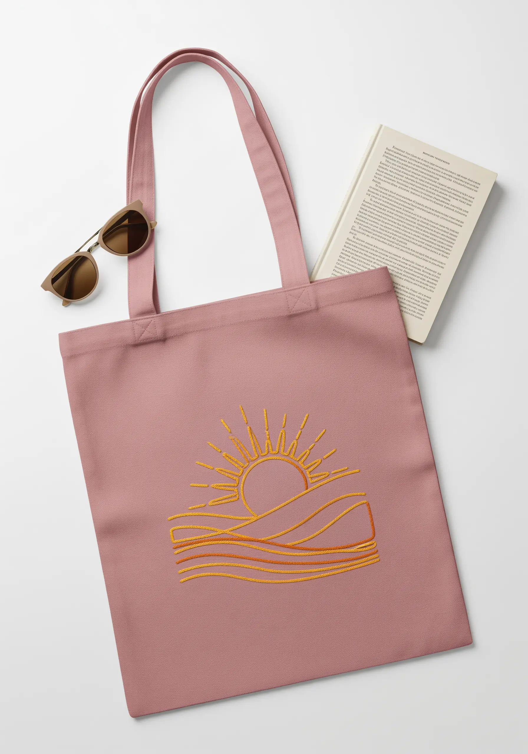 Minimalist line art of a sun over waves, stitched in shades of orange on a pink tote.