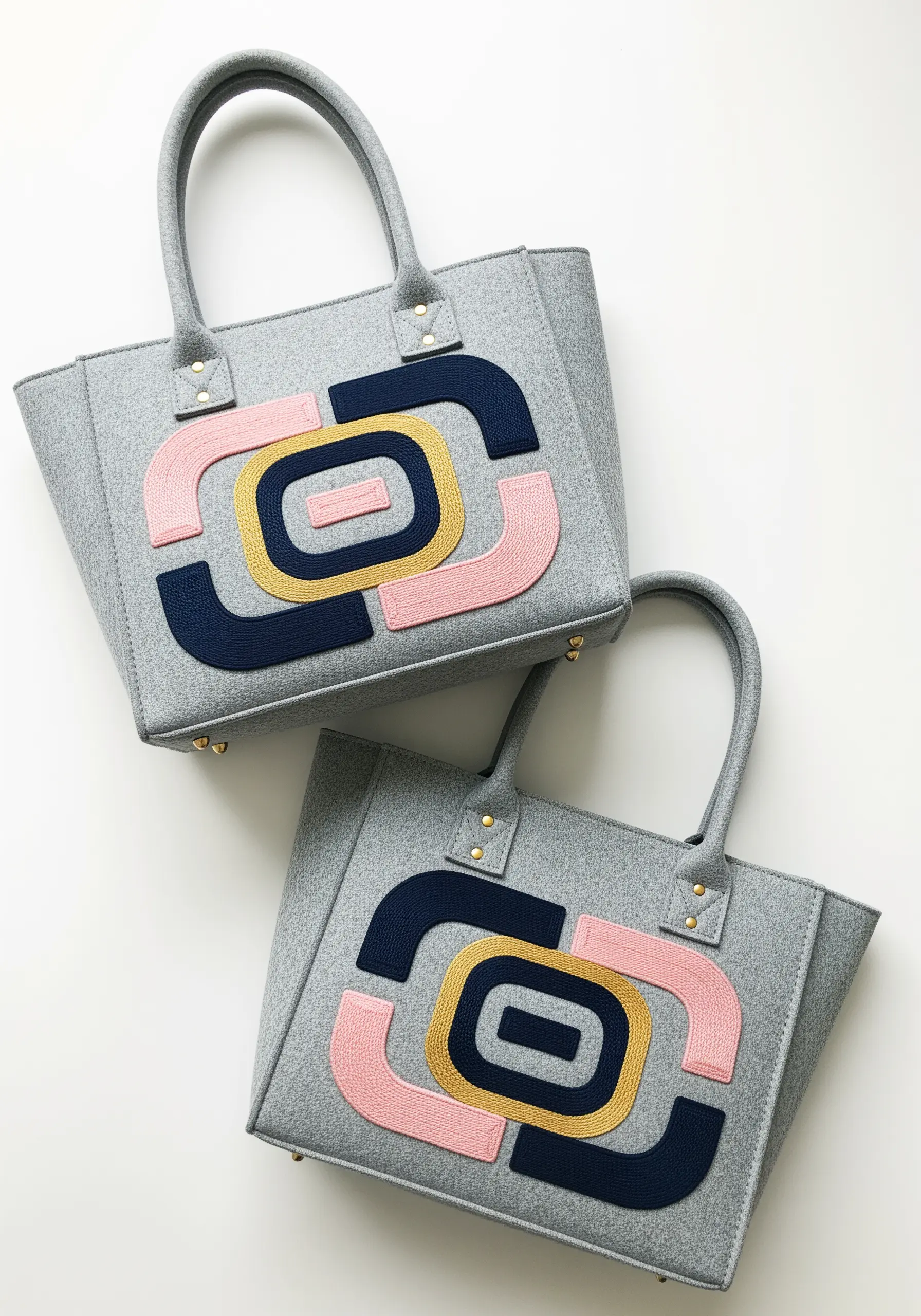 Gray felt tote bags with abstract geometric appliqué in pink, navy, and gold.