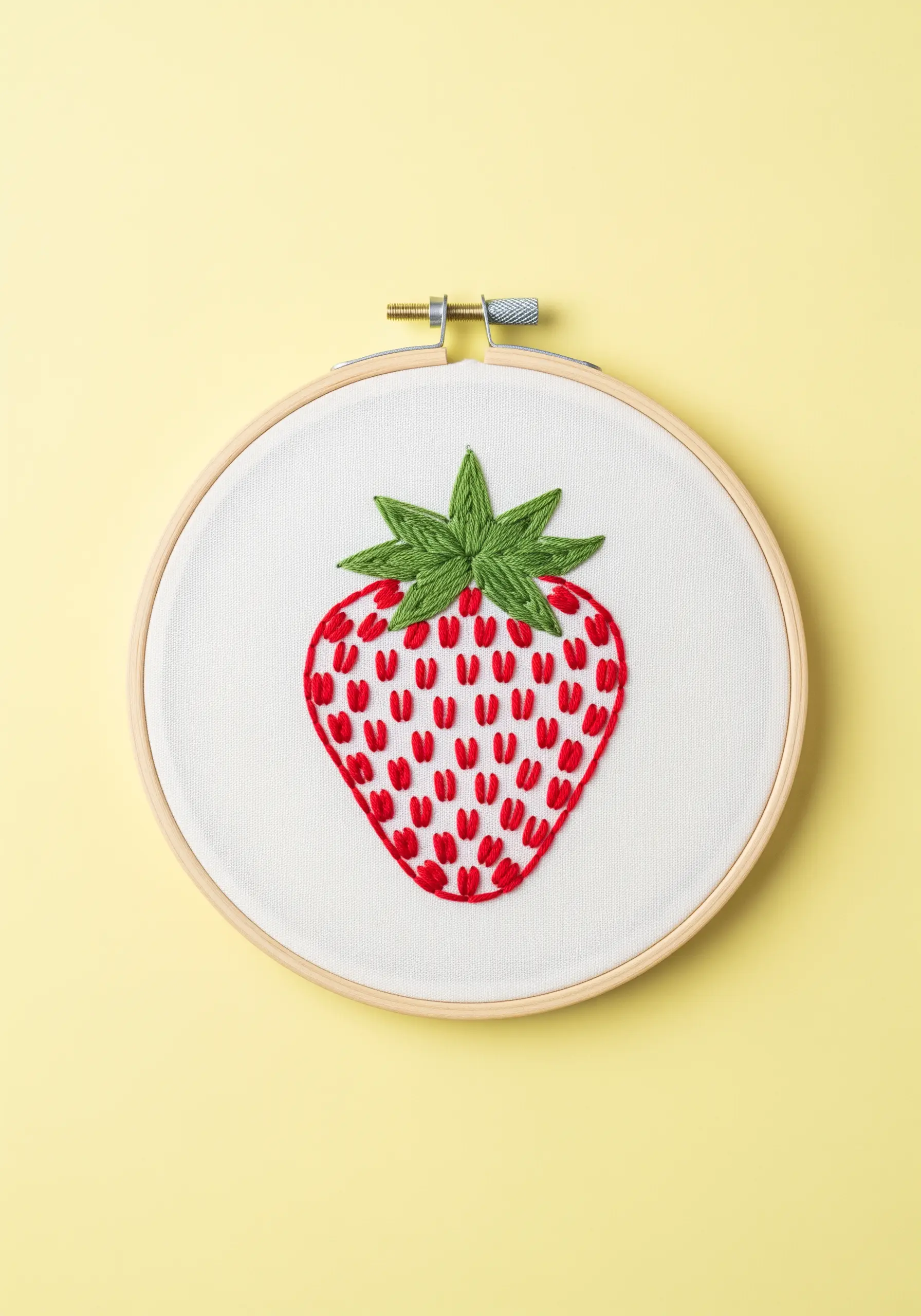 A stylized strawberry outlined in red with detached chain stitches for seeds.