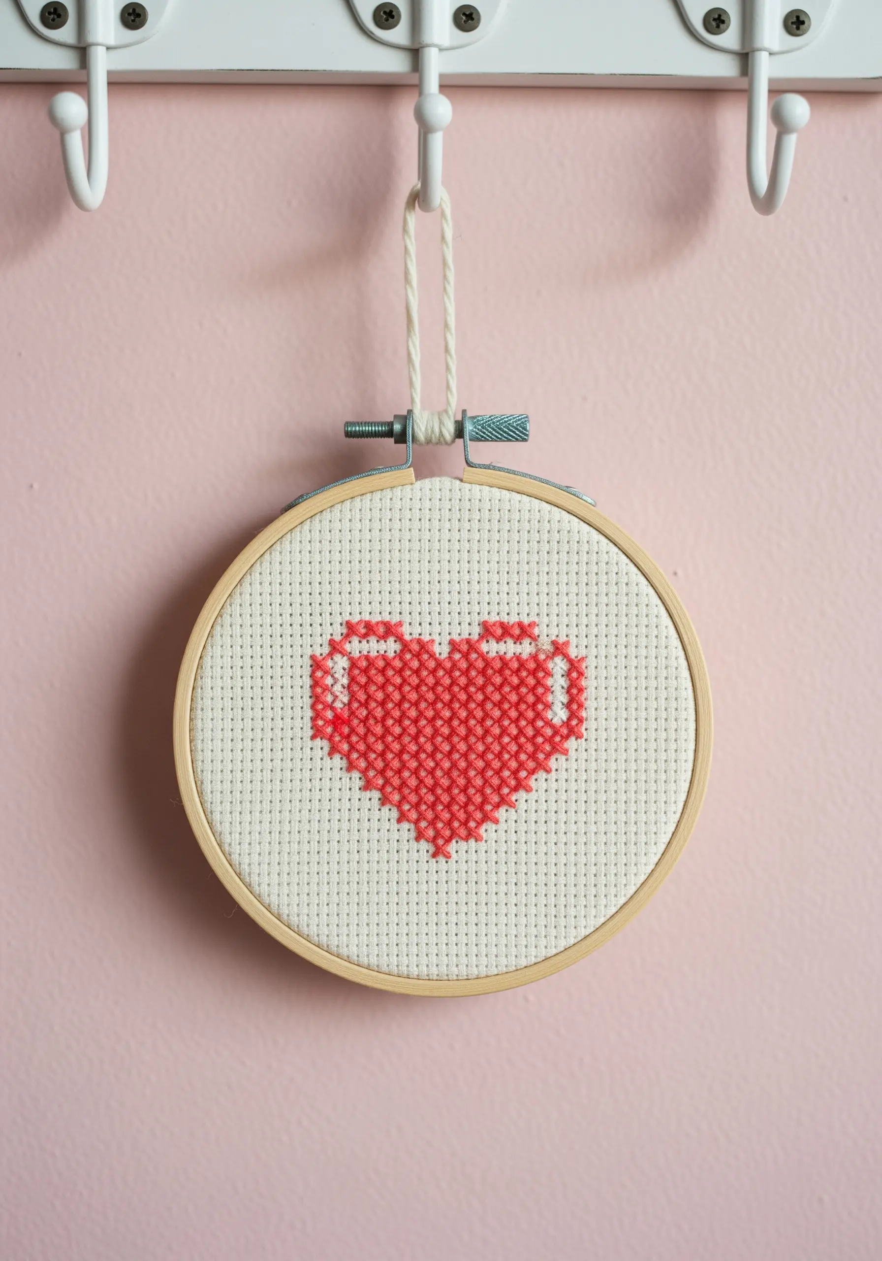 A pixelated heart design created with red cross-stitch on Aida cloth.