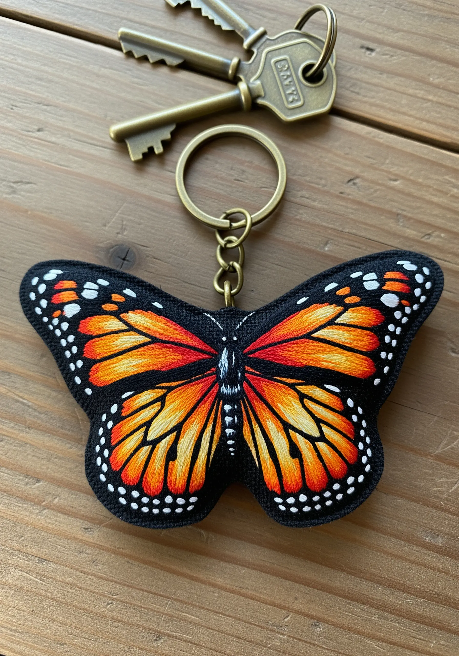 A freestanding embroidered monarch butterfly keychain with detailed thread-painted wings.