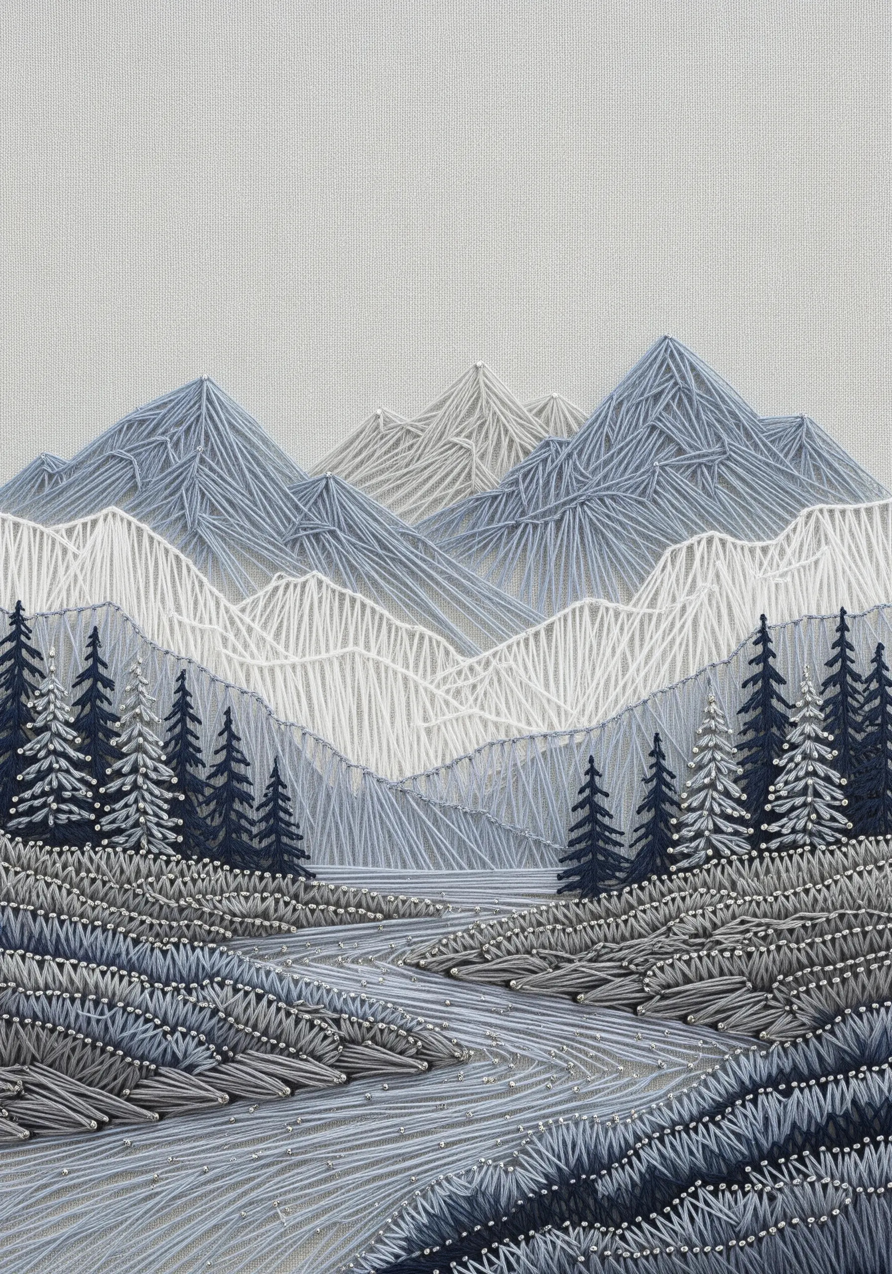 Monochromatic embroidery of a mountain landscape with layered grey and white threads.