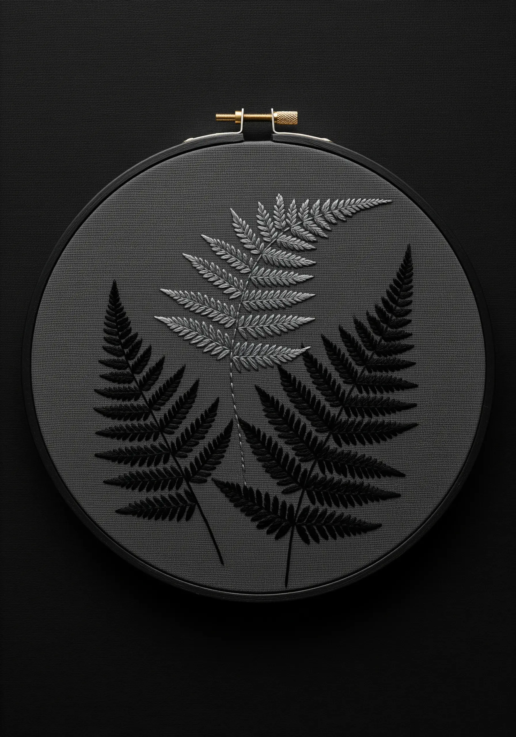 Three embroidered ferns on dark grey fabric; one in silver, two in black.