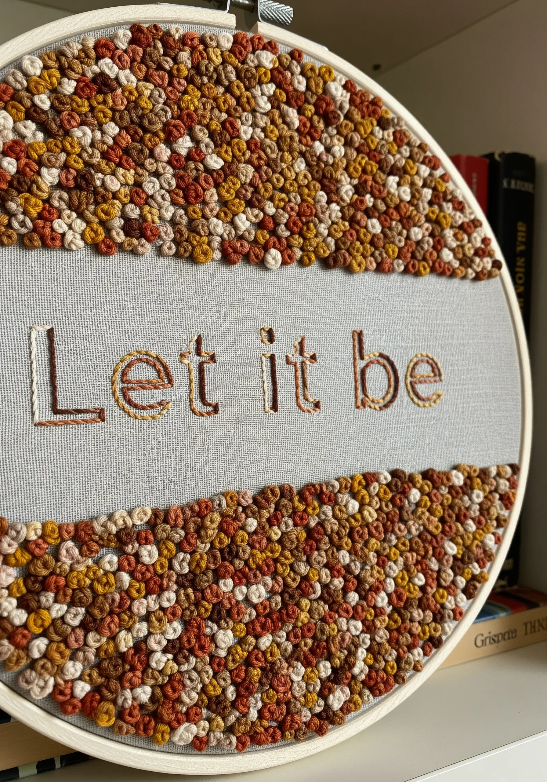 Negative space lettering framed by a dense texture of colorful French knots.