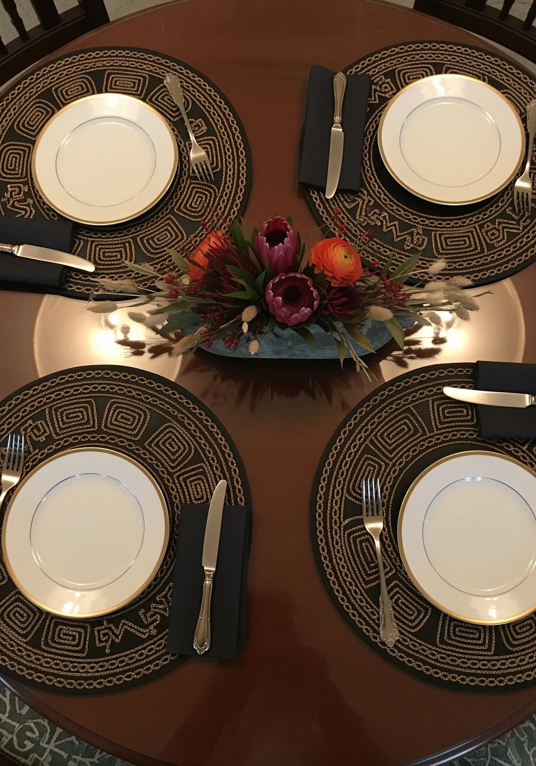 Round black placemats with a thick, raised geometric spiral embroidered in gold metallic thread.