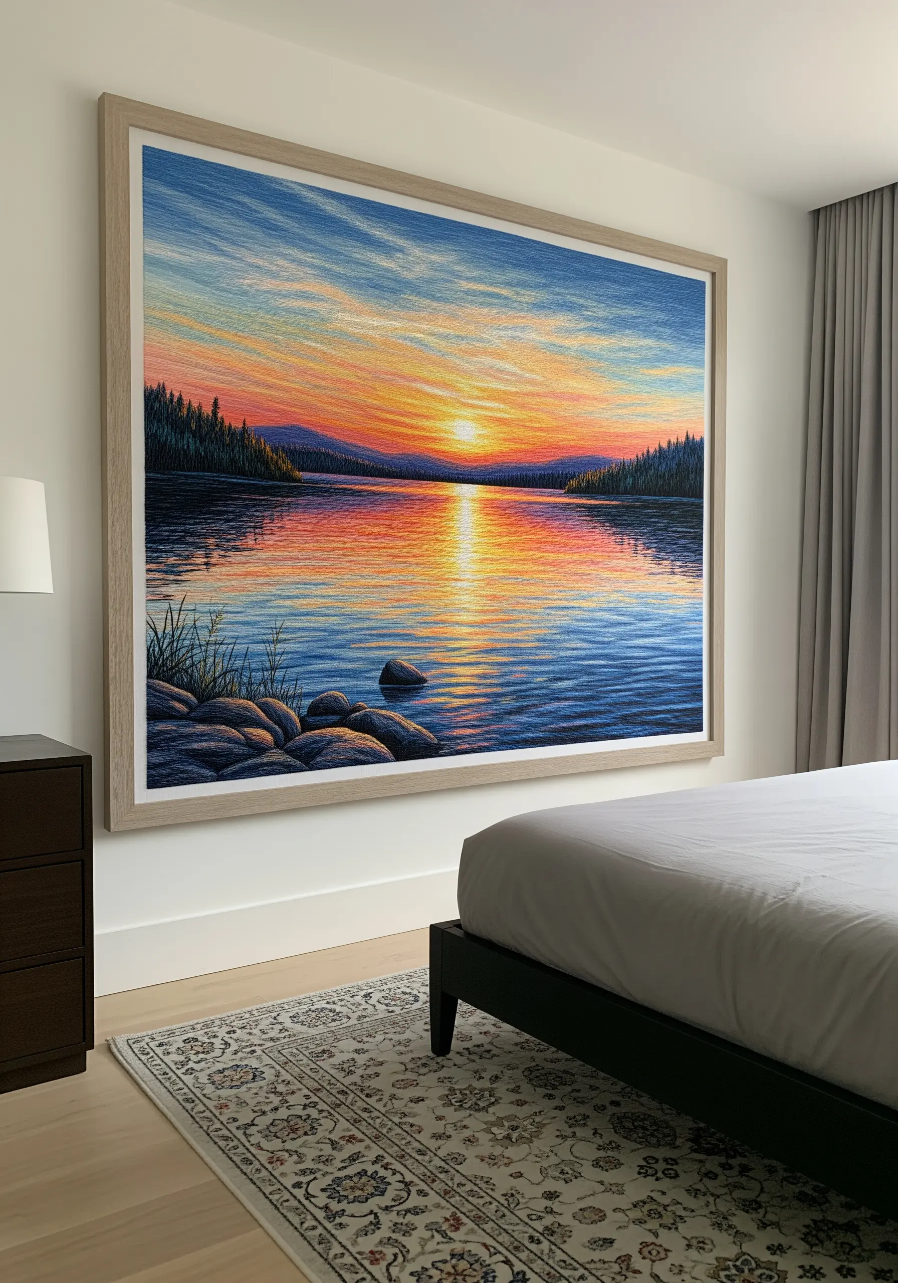 A large framed thread-painted landscape embroidery of a sunset over a lake.