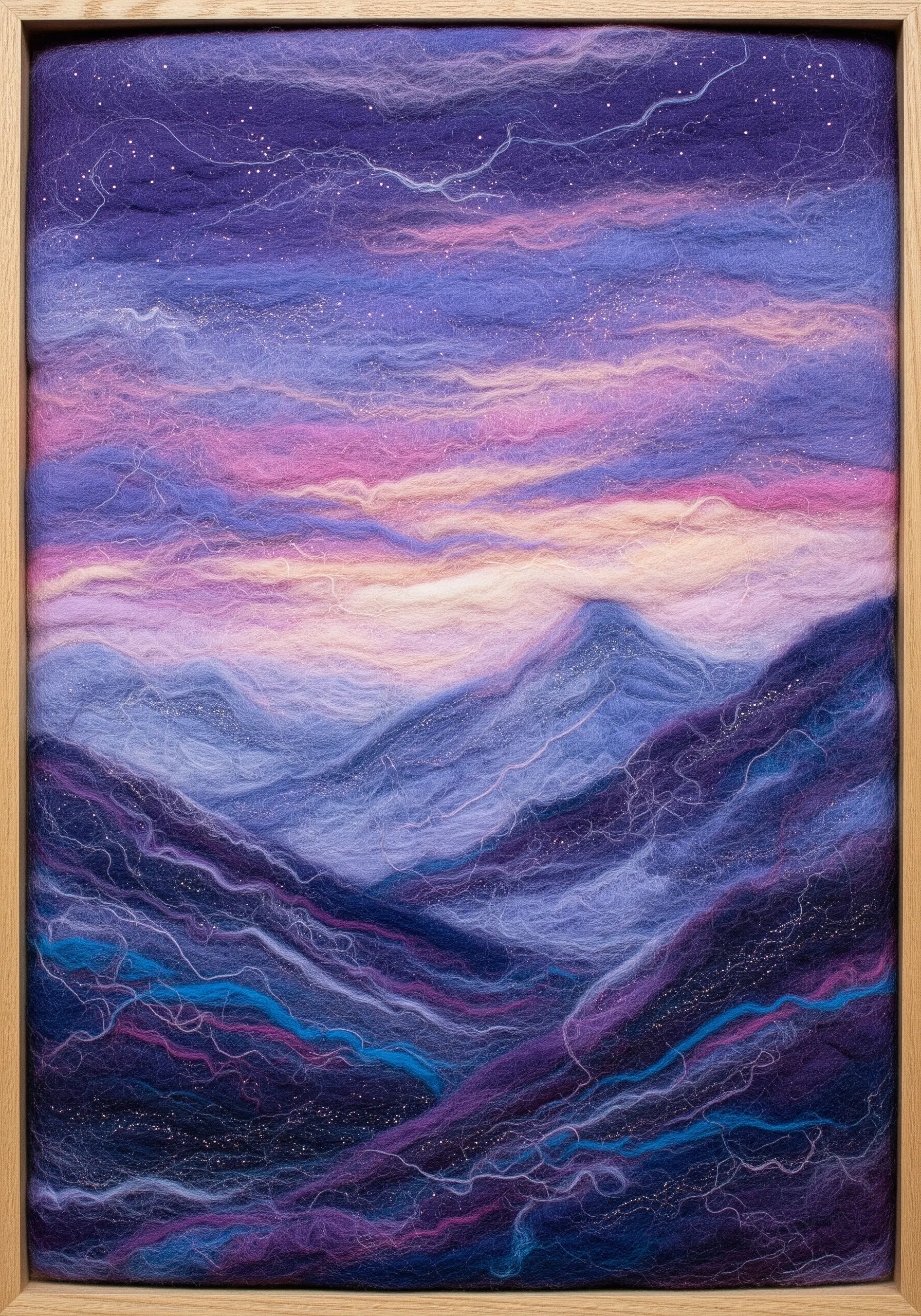 A felted wool landscape depicting a purple and pink sunset over mountains, framed in a light wood box.