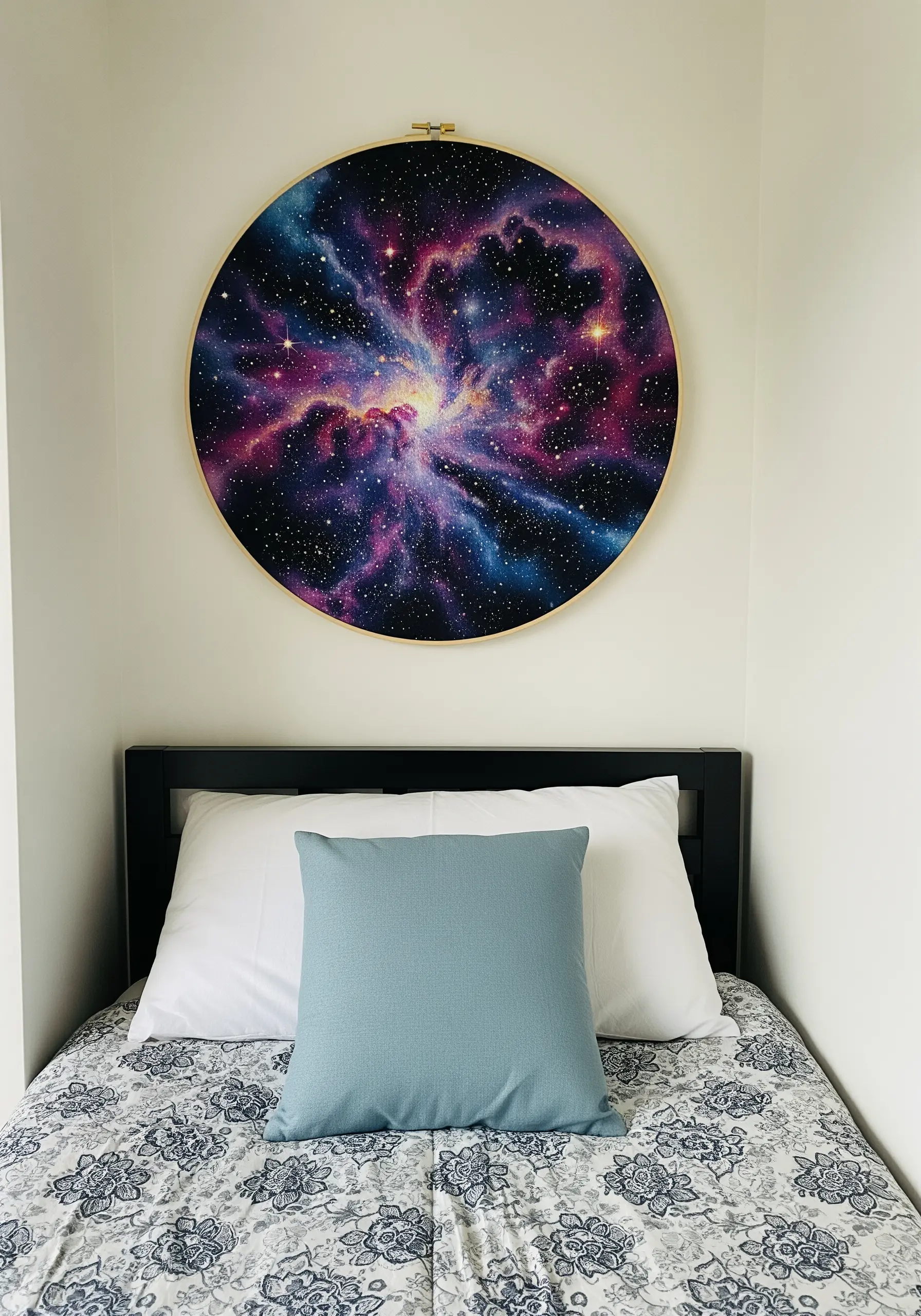 A large embroidery hoop filled with a vibrant, thread-painted nebula in shades of purple and pink.