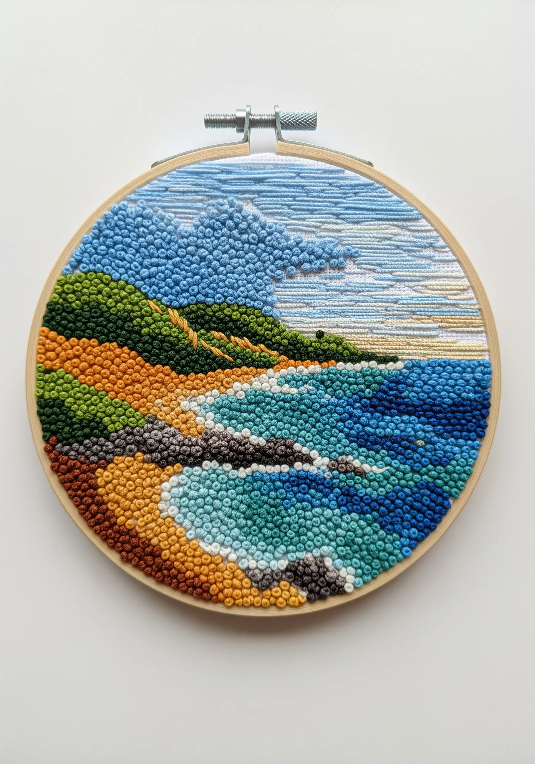 Embroidered coastal landscape using French knots for the beach and satin stitches for the sky.