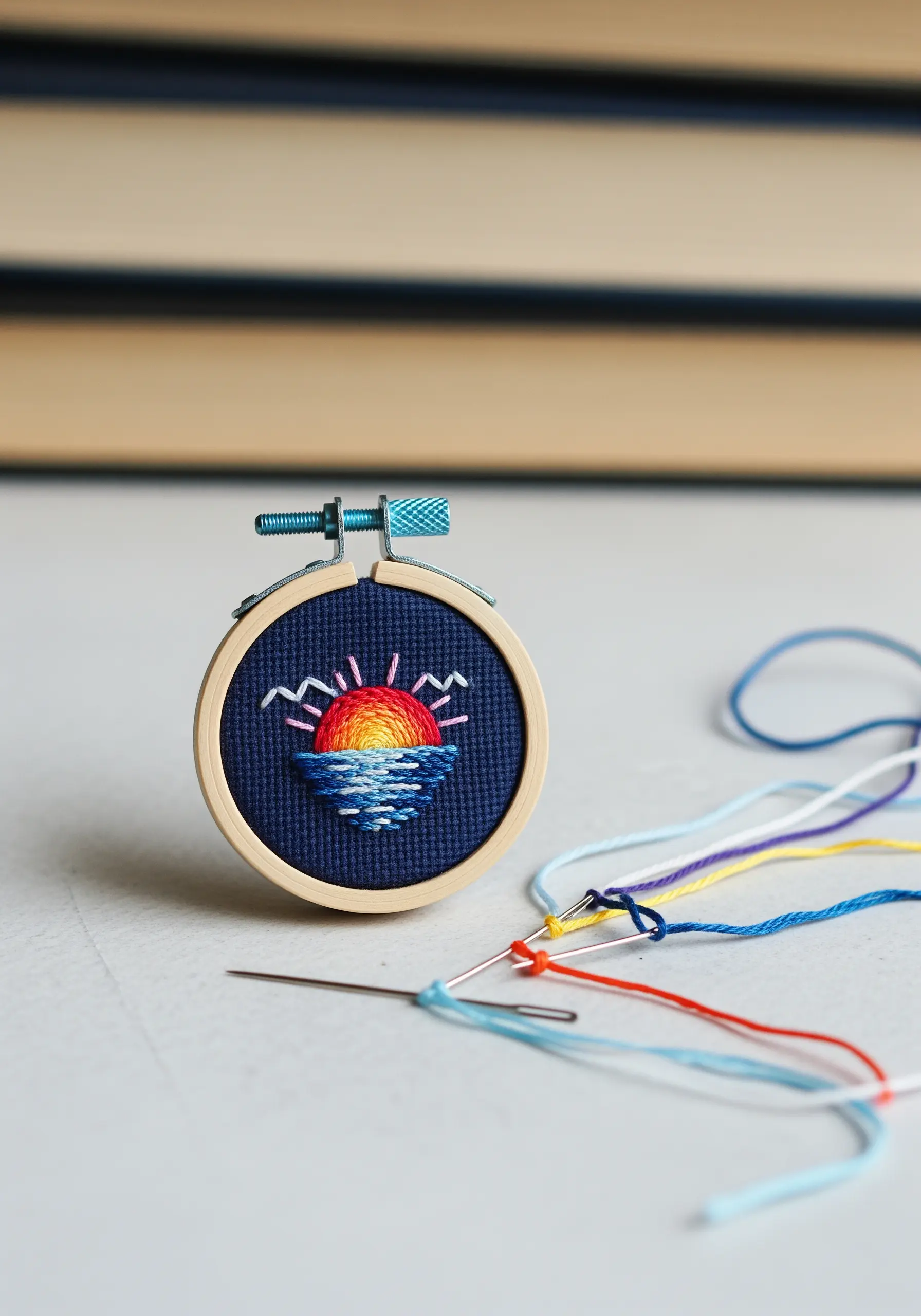 A miniature embroidery hoop with a vibrant thread-painted sunset over the ocean