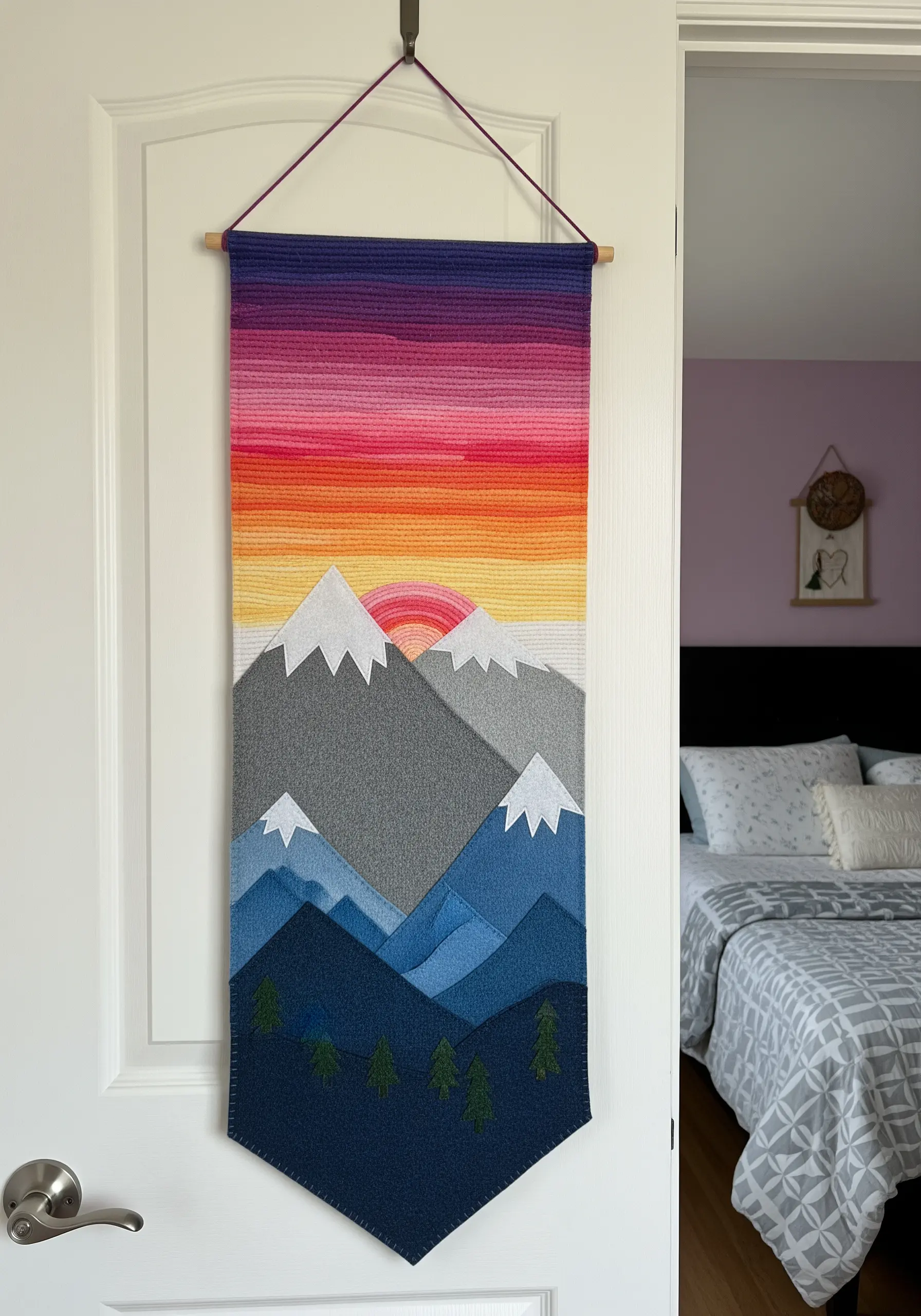 A textile wall hanging of a mountain sunset with a smooth, colorful gradient sky.
