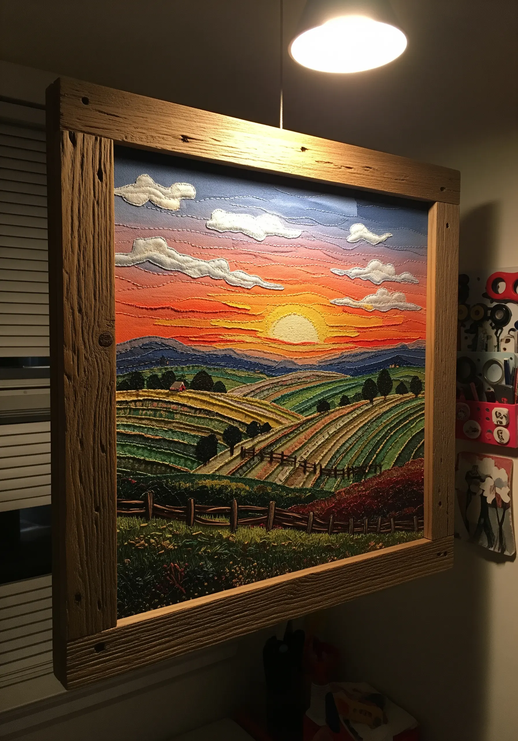 A framed, intricately embroidered landscape of rolling hills at sunset with textured clouds.