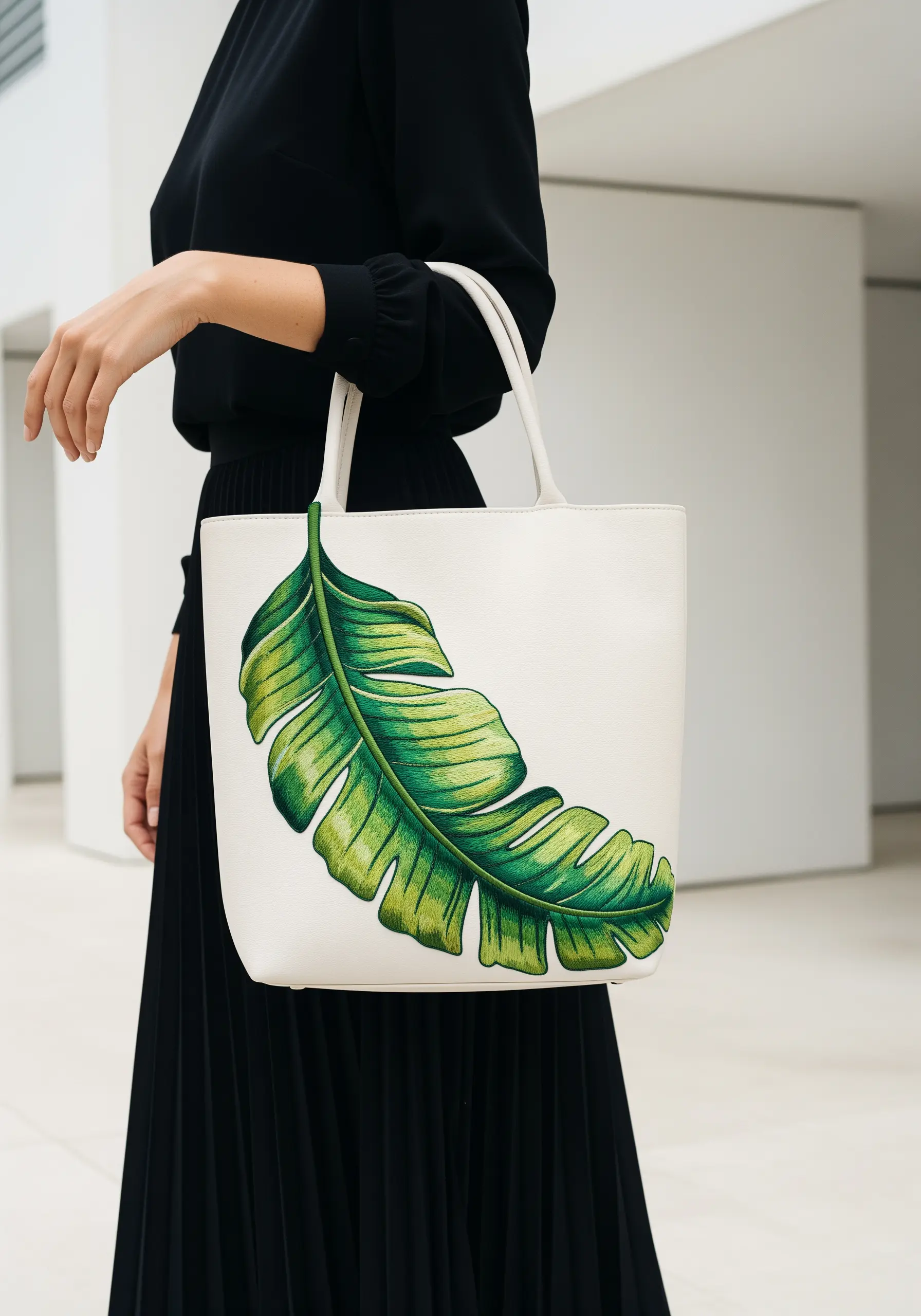 A large banana leaf on a white tote, embroidered with greens and yellows to look like a watercolor painting.