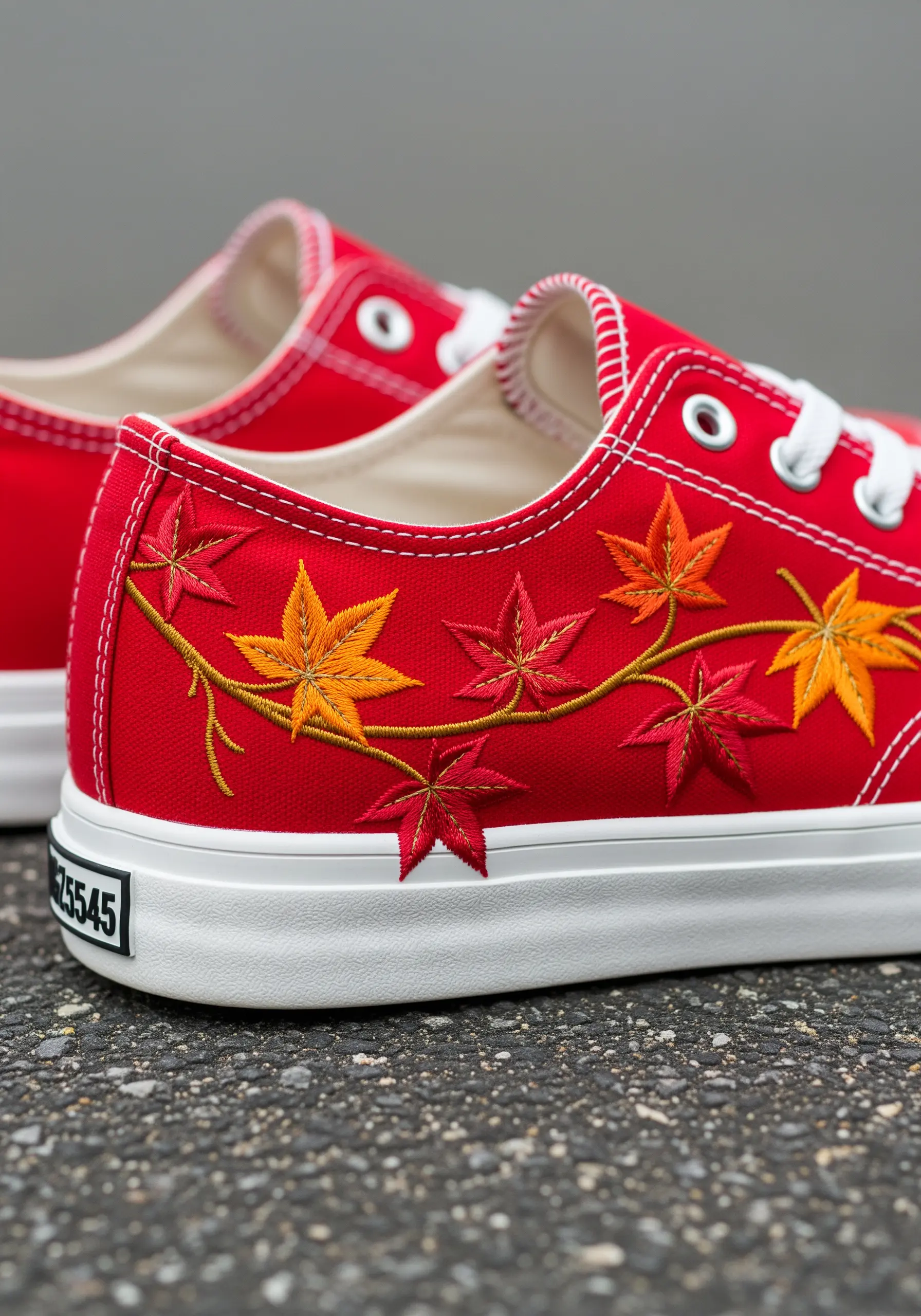A vine of autumn-colored maple leaves embroidered on the side of a bright red sneaker.